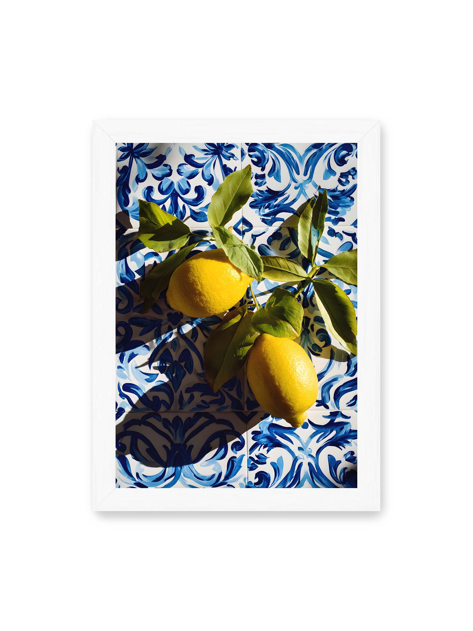 21x30 cm, weißer Rahmen – Zitronen mit Blättern auf blau gemusterten Fliesen mit starkem Licht und klaren Schatten.