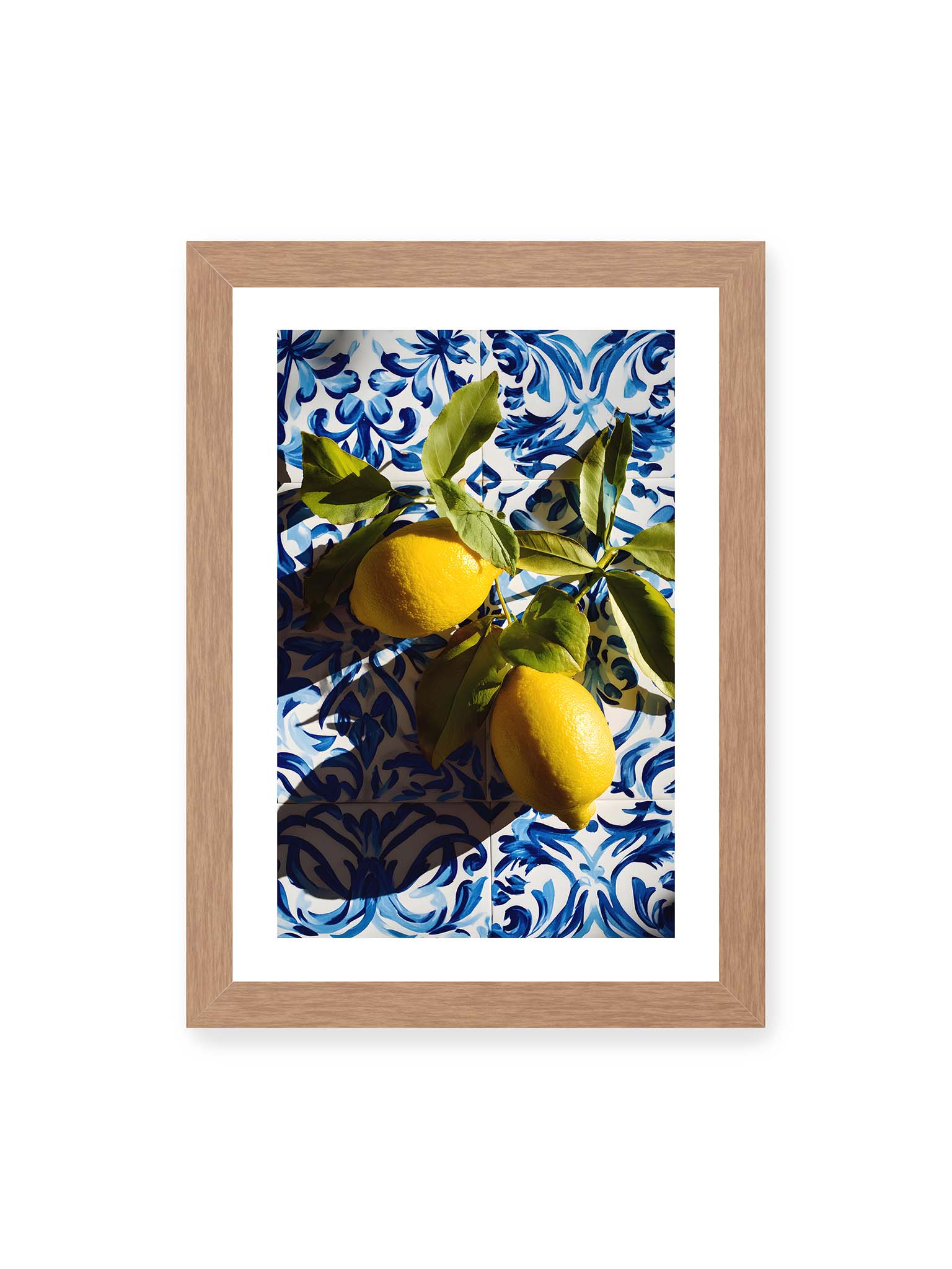 21x30 cm, weißer Galerie-Rand, Eichenrahmen – Zitronen mit Blättern auf blau gemusterten Fliesen mit starkem Licht und klaren Schatten.