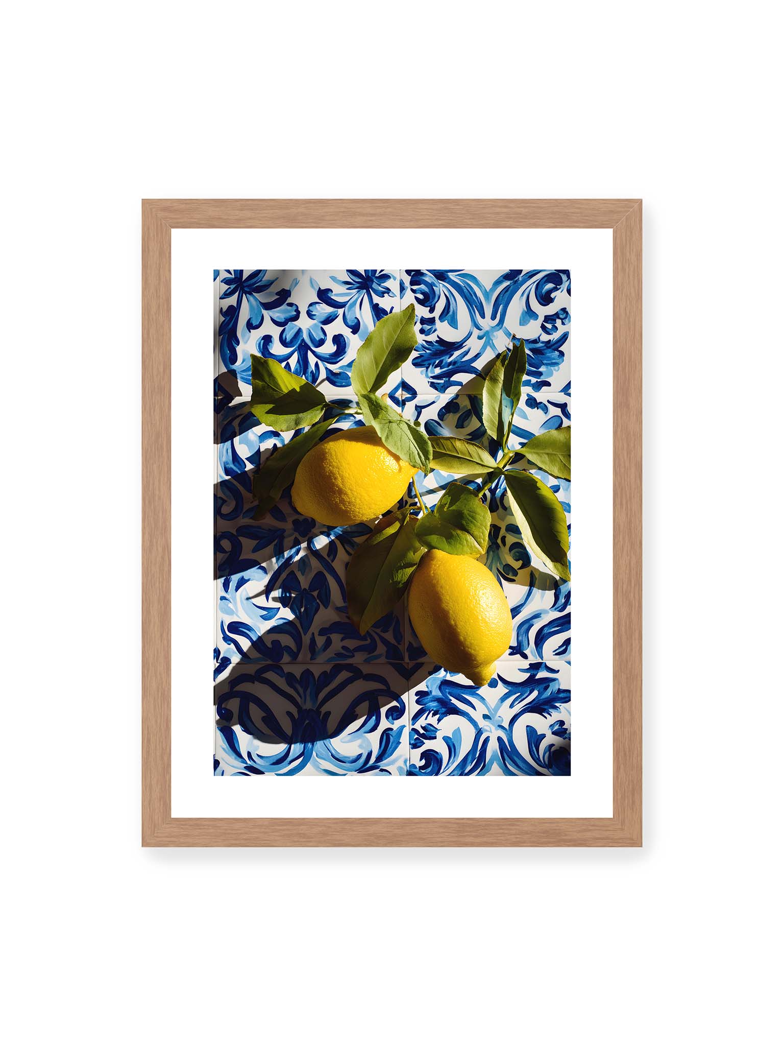 30x40 cm, weißer Galerie-Rand, Eichenrahmen – Zitronen mit Blättern auf blau gemusterten Fliesen mit starkem Licht und klaren Schatten.