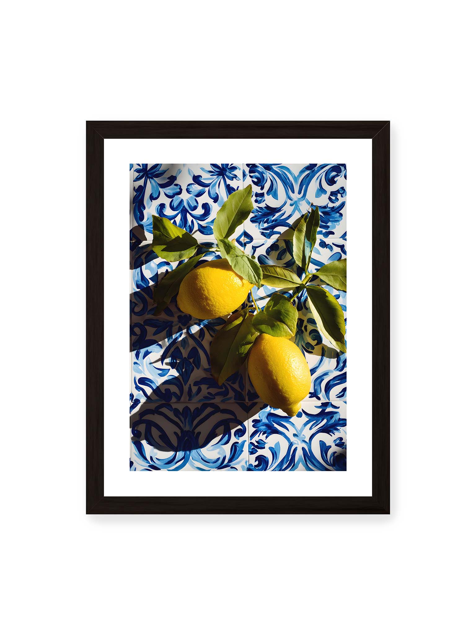 30x40 cm, weißer Galerie-Rand, schwarzer Rahmen – Zitronen mit Blättern auf blau gemusterten Fliesen mit starkem Licht und klaren Schatten.