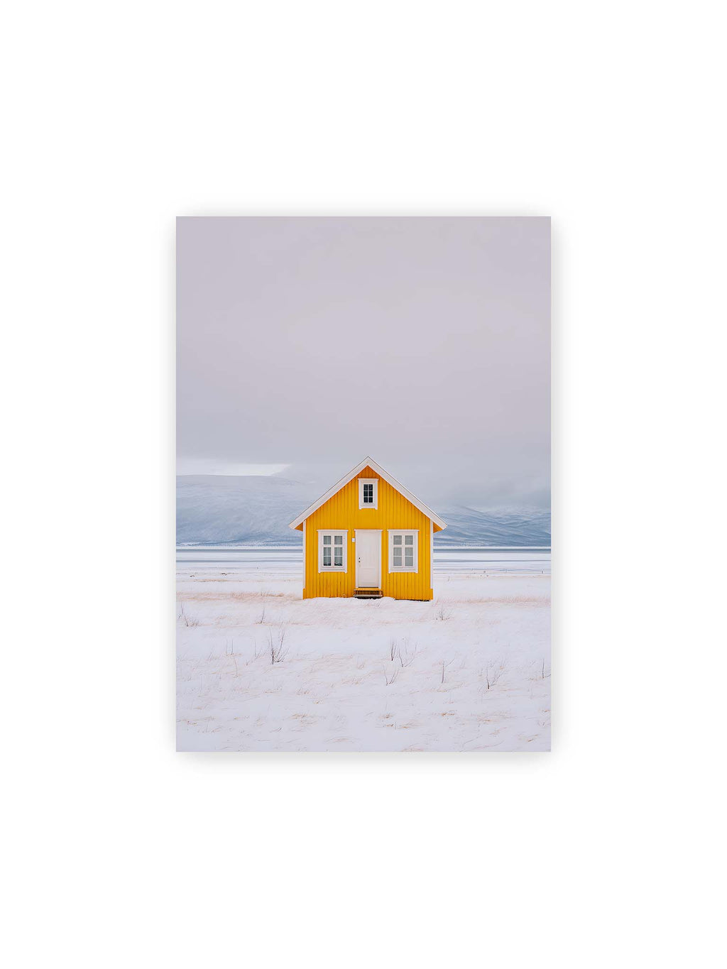 21x30 cm – Gelbes Haus steht allein in weiter verschneiter Landschaft mit Bergen im Hintergrund und grauem Himmel.