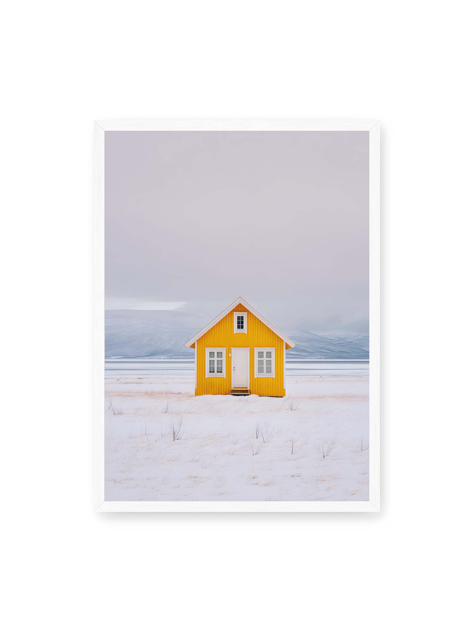 50x70 cm, weißer Rahmen – Gelbes Haus steht allein in weiter verschneiter Landschaft mit Bergen im Hintergrund und grauem Himmel.