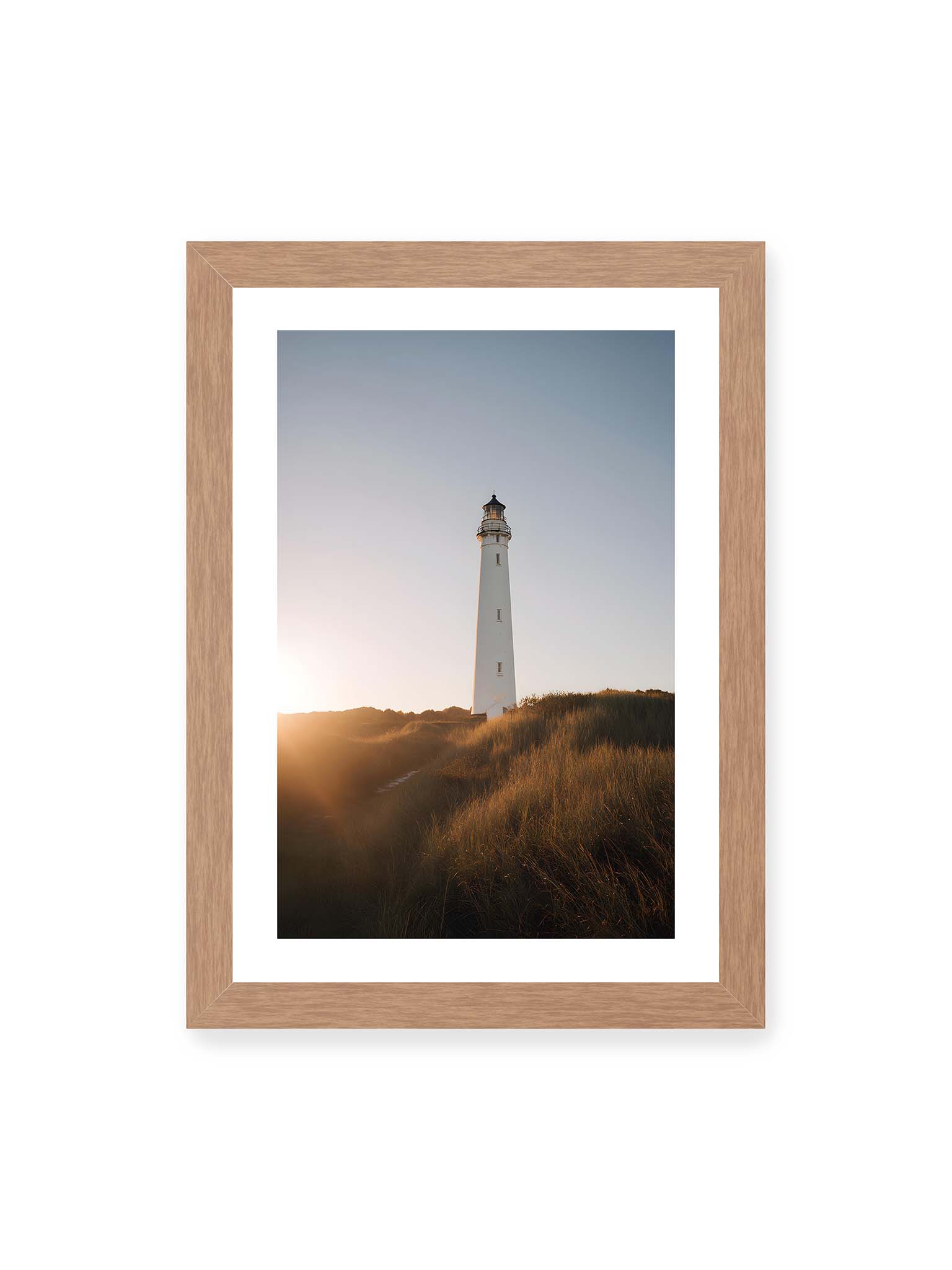 21x30 cm, weißer Galerie-Rand, Eichenrahmen – Weißer Leuchtturm über Dünen im warmen Abendlicht mit sanftem Himmel im Hintergrund.