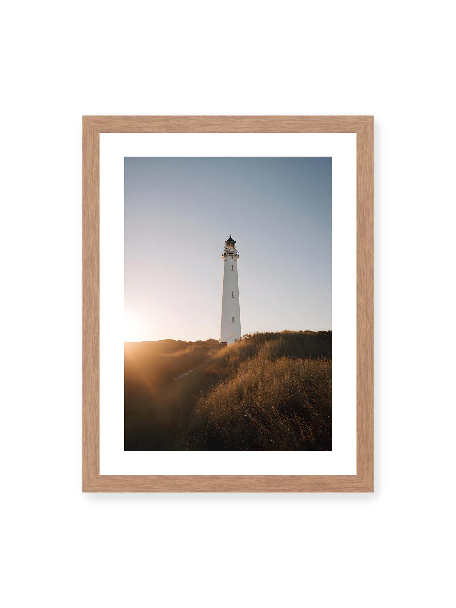 30x40 cm, weißer Galerie-Rand, Eichenrahmen – Weißer Leuchtturm über Dünen im warmen Abendlicht mit sanftem Himmel im Hintergrund.