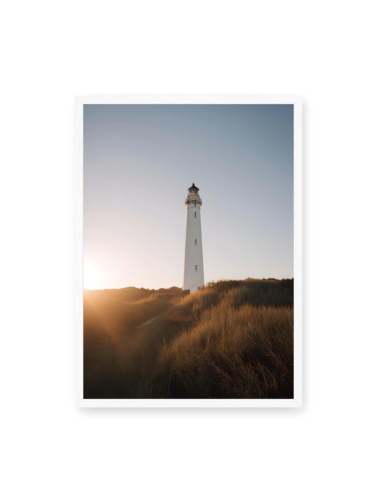 50x70 cm, weißer Rahmen – Weißer Leuchtturm über Dünen im warmen Abendlicht mit sanftem Himmel im Hintergrund.