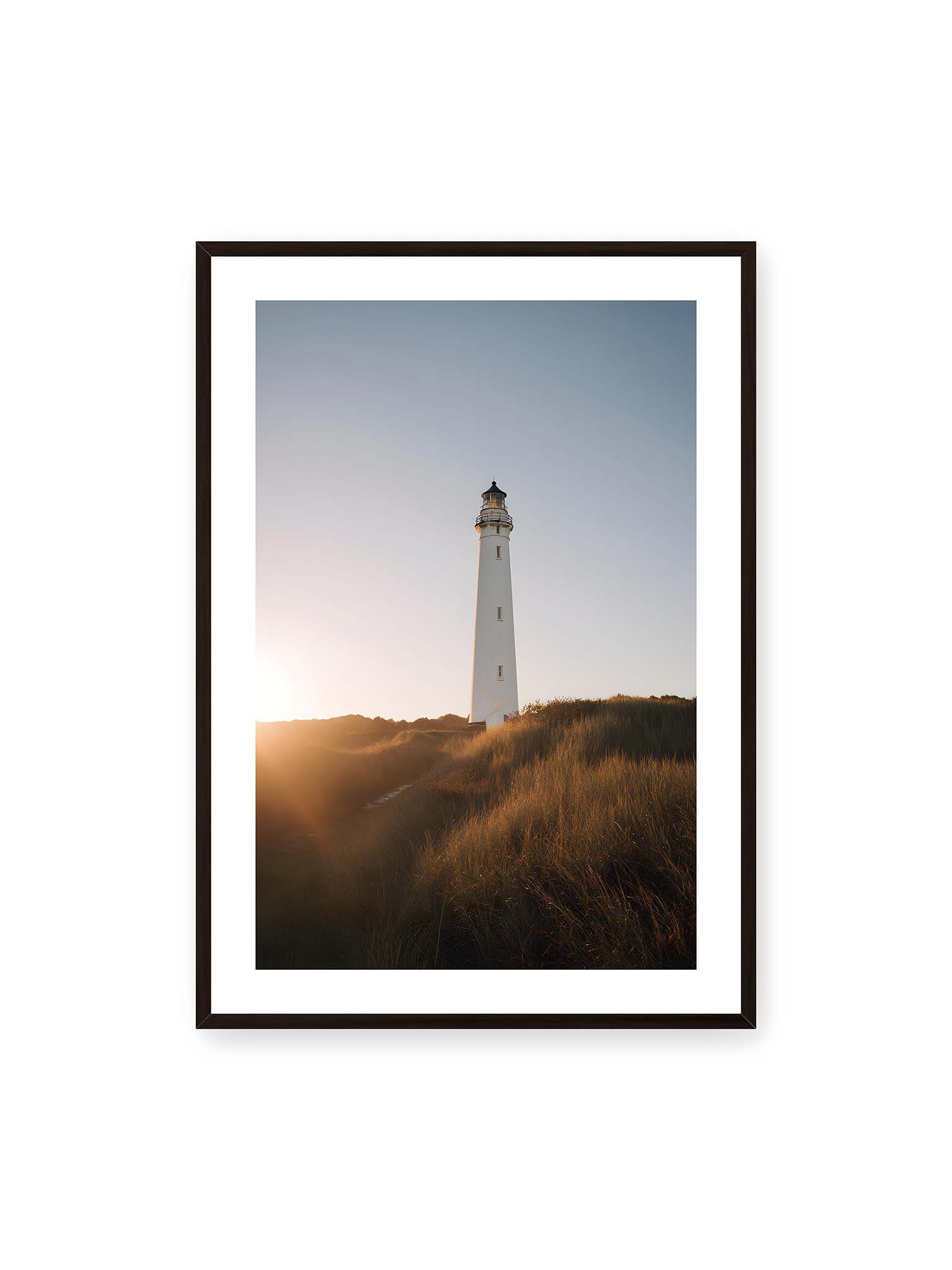 70x100 cm, weißer Galerie-Rand, schwarzer Rahmen – Weißer Leuchtturm über Dünen im warmen Abendlicht mit sanftem Himmel im Hintergrund.