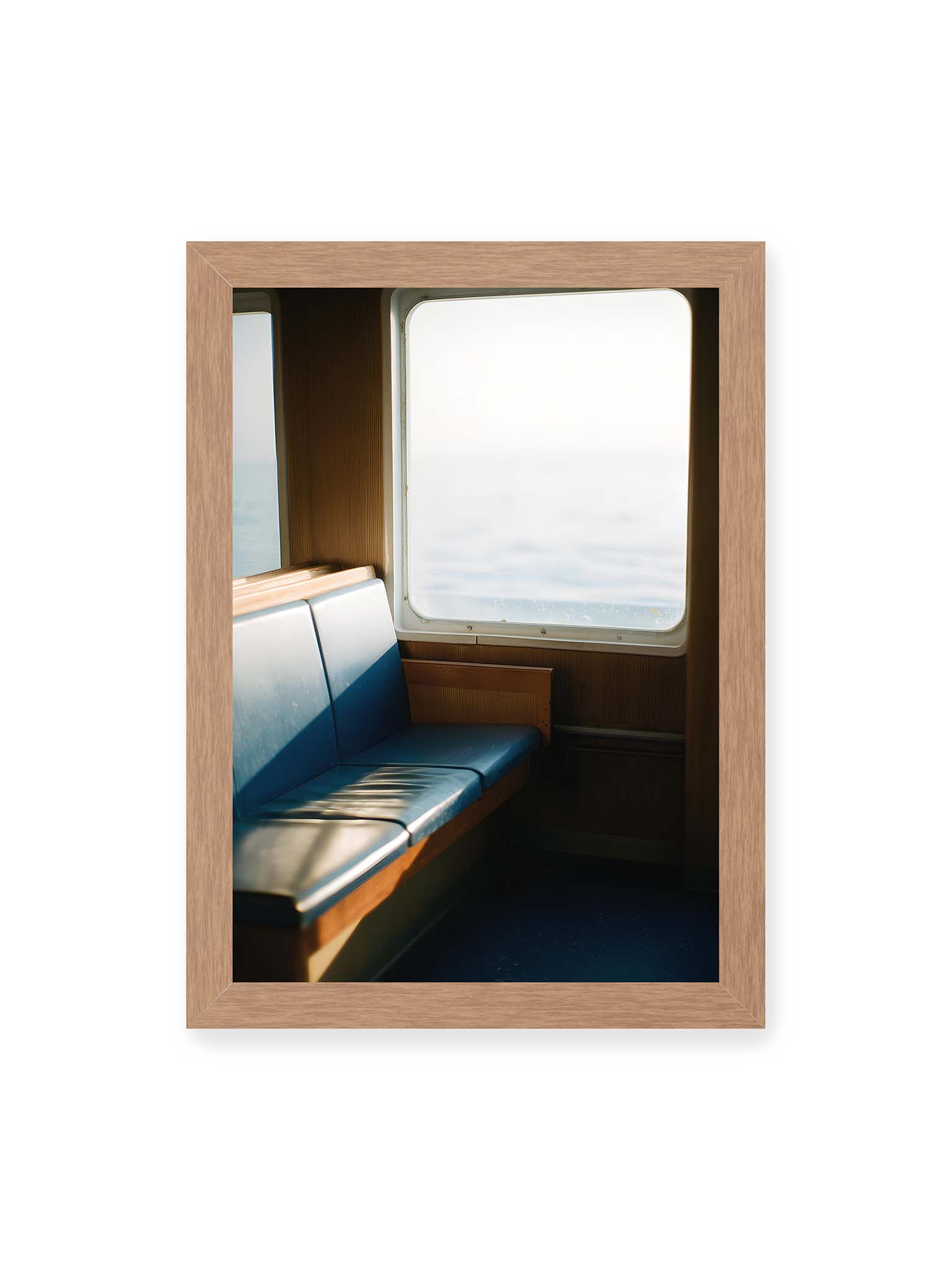 21x30 cm, Eichenrahmen – Leerer Sitzplatz neben einem Fenster mit warmem Licht und unscharfer Aussicht auf das offene Meer.