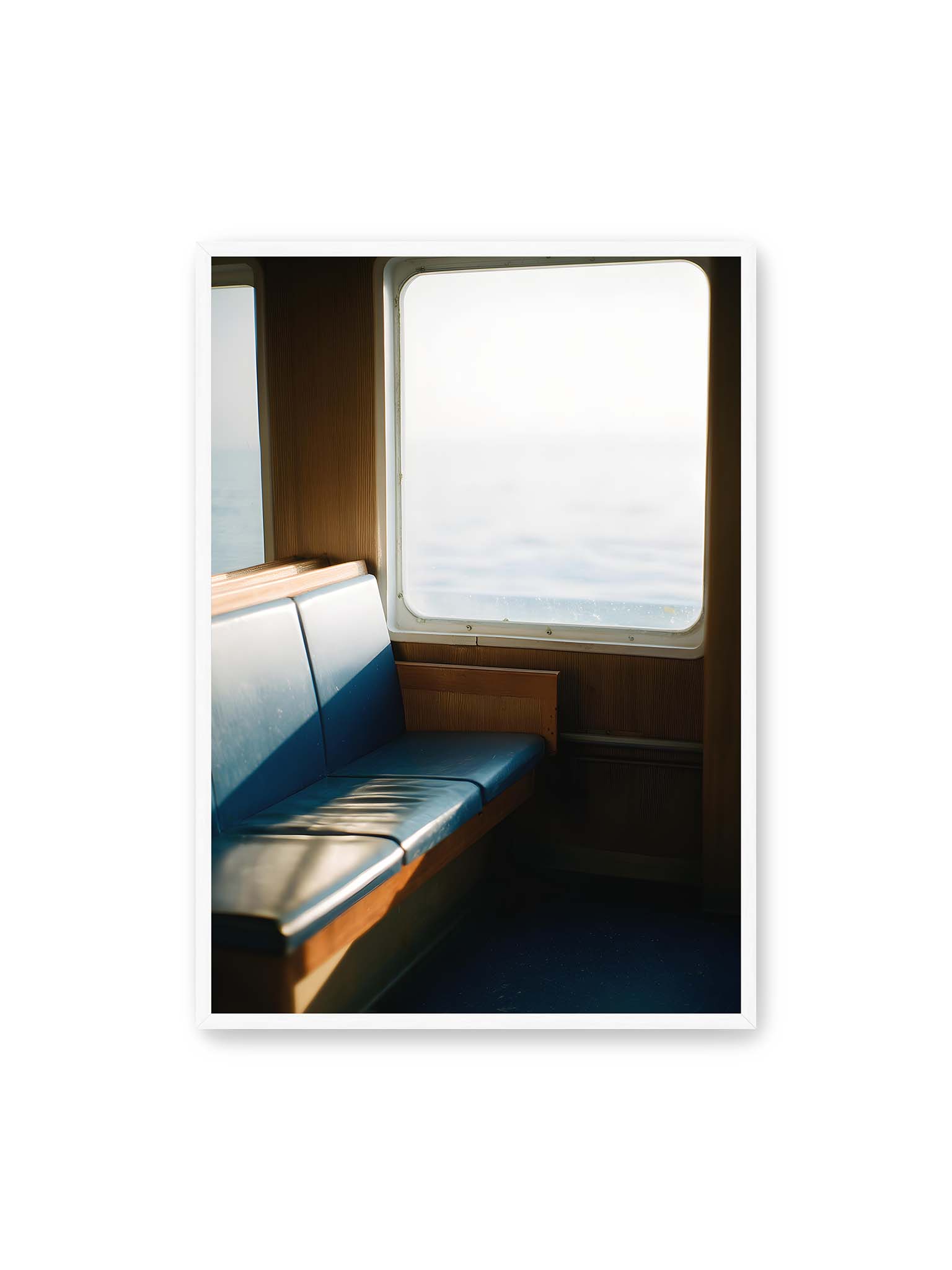 70x100 cm, weißer Rahmen – Leerer Sitzplatz neben einem Fenster mit warmem Licht und unscharfer Aussicht auf das offene Meer.