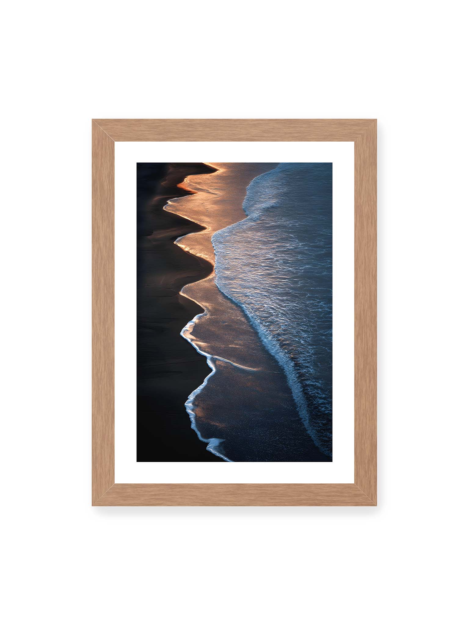 21x30 cm, weißer Galerie-Rand, Eichenrahmen – Goldene Wellenlinien treffen auf dunklen Strand mit starkem Kontrast zwischen Licht und Schatten entlang der Küste.