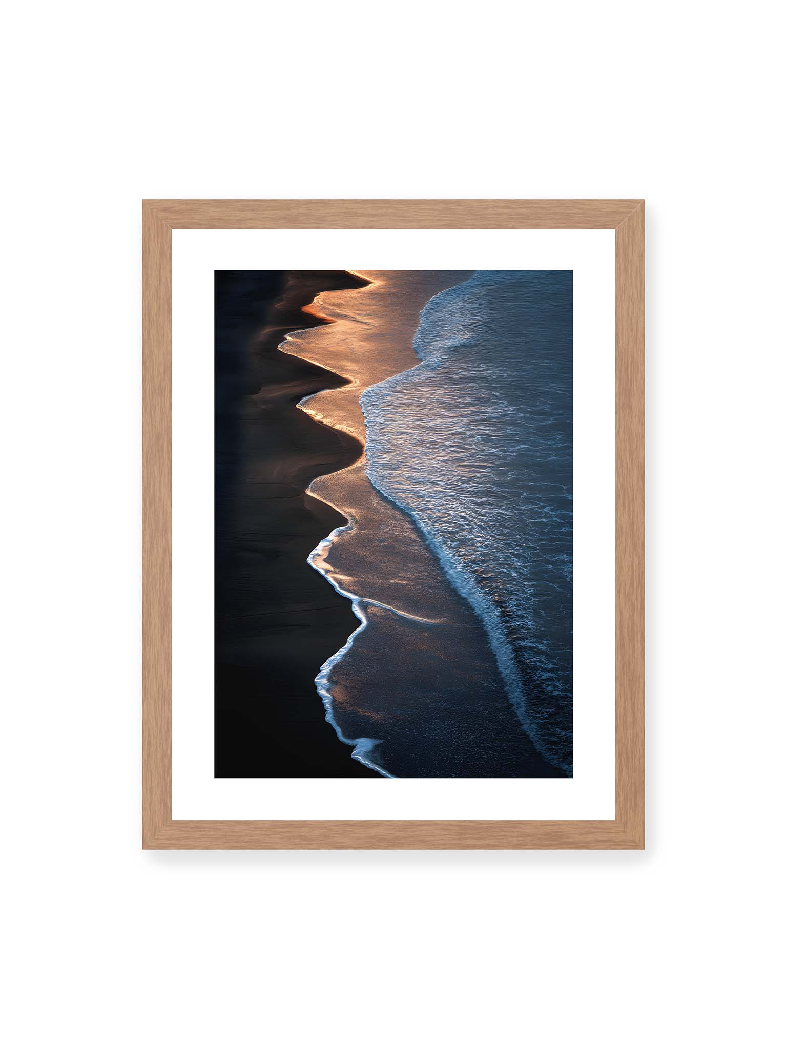 30x40 cm, weißer Galerie-Rand, Eichenrahmen – Goldene Wellenlinien treffen auf dunklen Strand mit starkem Kontrast zwischen Licht und Schatten entlang der Küste.