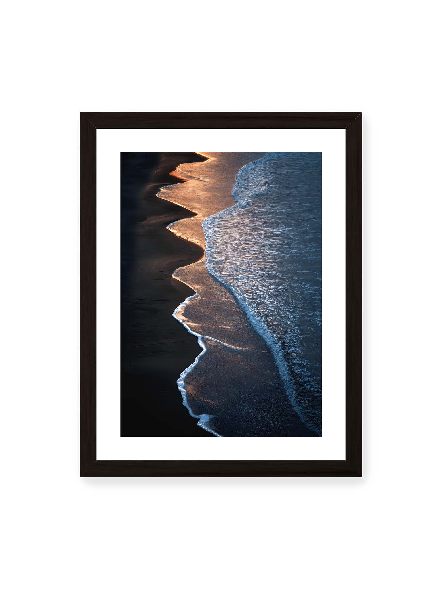 30x40 cm, weißer Galerie-Rand, schwarzer Rahmen – Goldene Wellenlinien treffen auf dunklen Strand mit starkem Kontrast zwischen Licht und Schatten entlang der Küste.