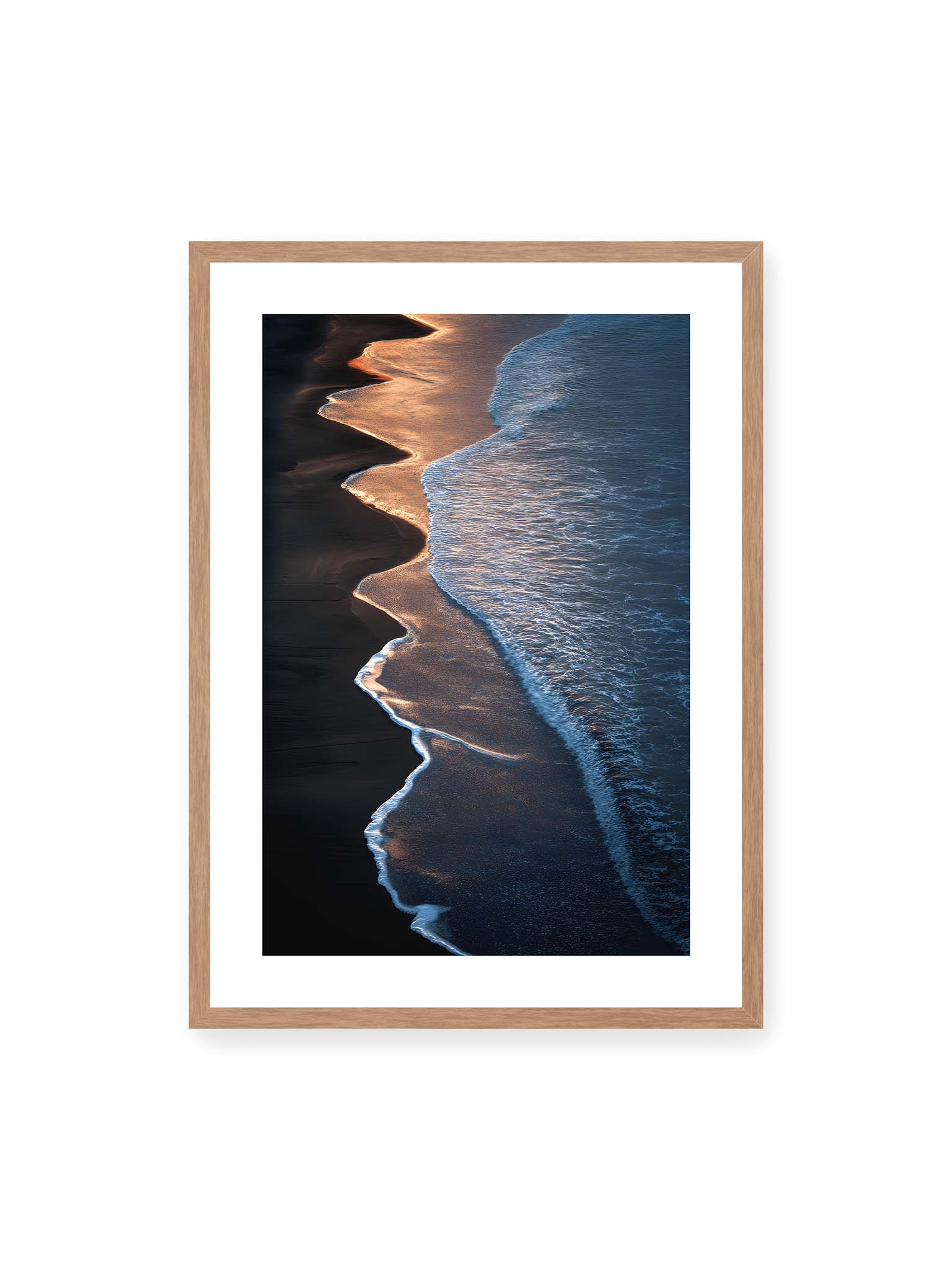 50x70 cm, weißer Galerie-Rand, Eichenrahmen – Goldene Wellenlinien treffen auf dunklen Strand mit starkem Kontrast zwischen Licht und Schatten entlang der Küste.