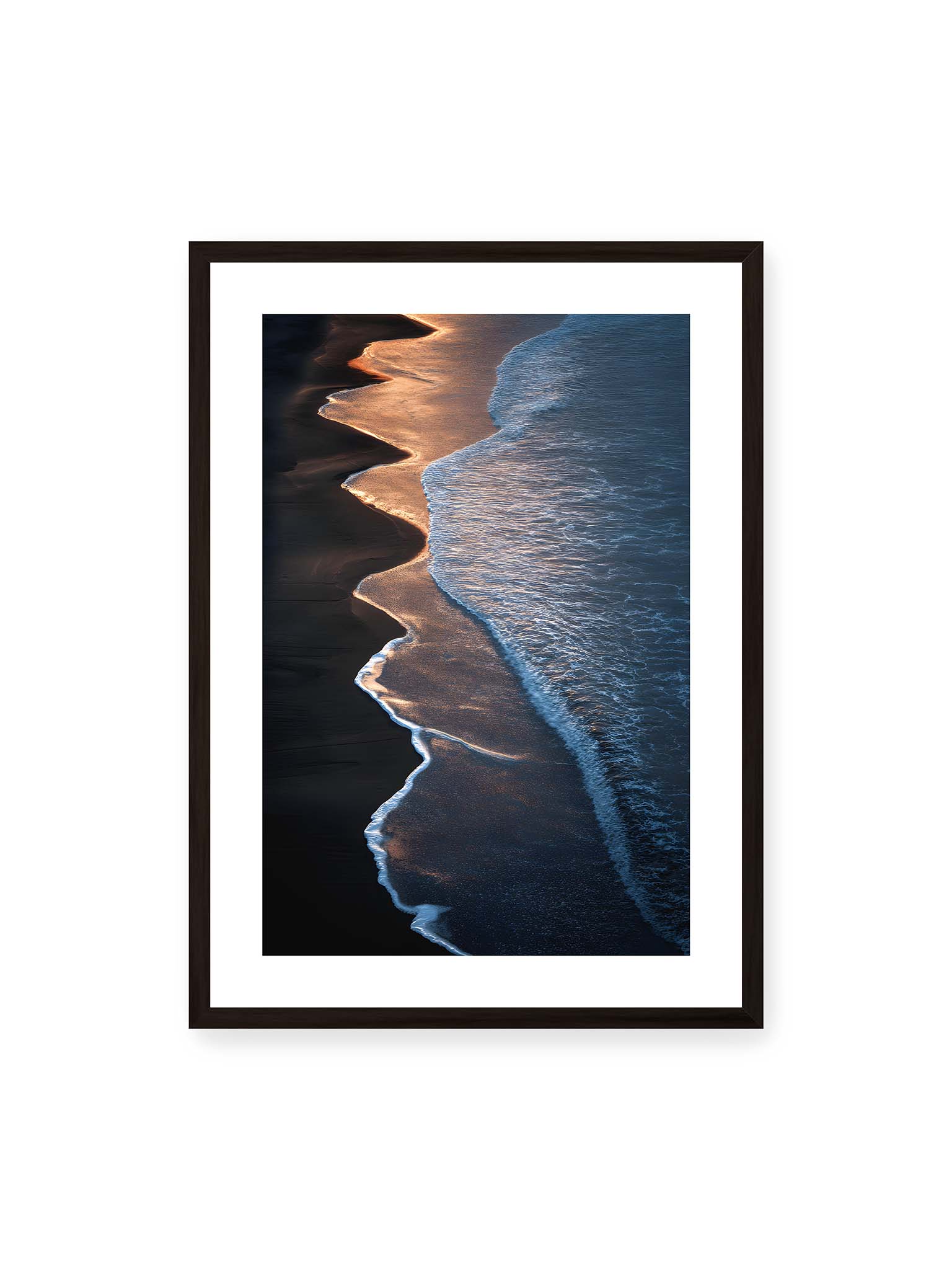 50x70 cm, weißer Galerie-Rand, schwarzer Rahmen – Goldene Wellenlinien treffen auf dunklen Strand mit starkem Kontrast zwischen Licht und Schatten entlang der Küste.