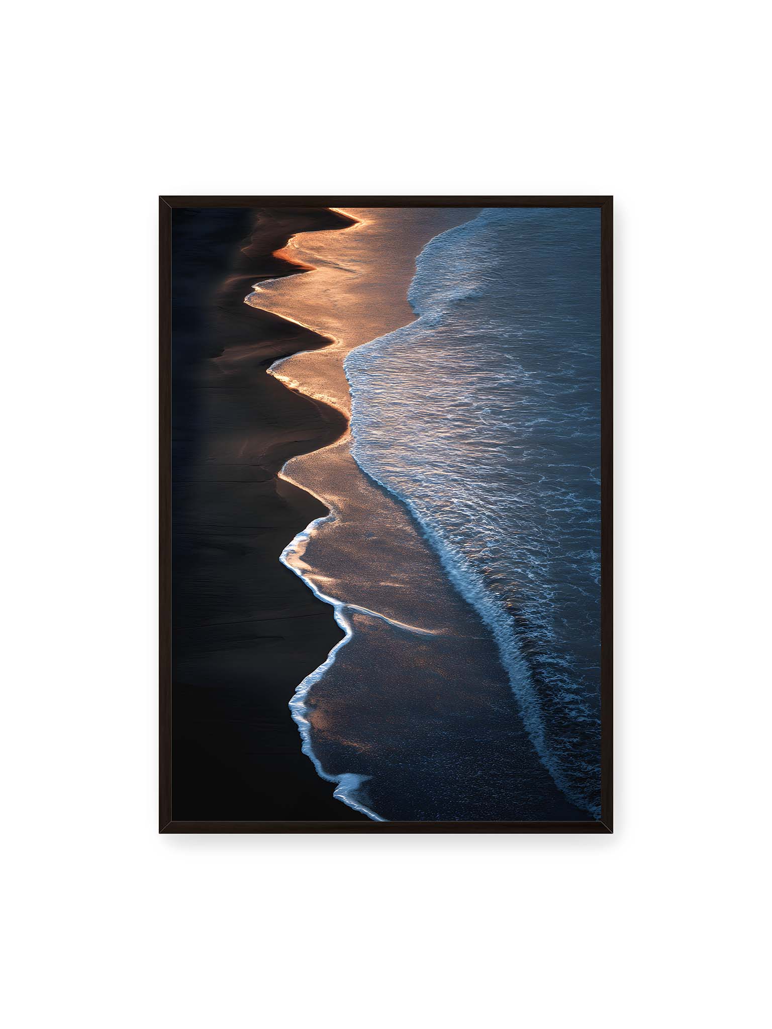 70x100 cm, schwarzer Rahmen – Goldene Wellenlinien treffen auf dunklen Strand mit starkem Kontrast zwischen Licht und Schatten entlang der Küste.