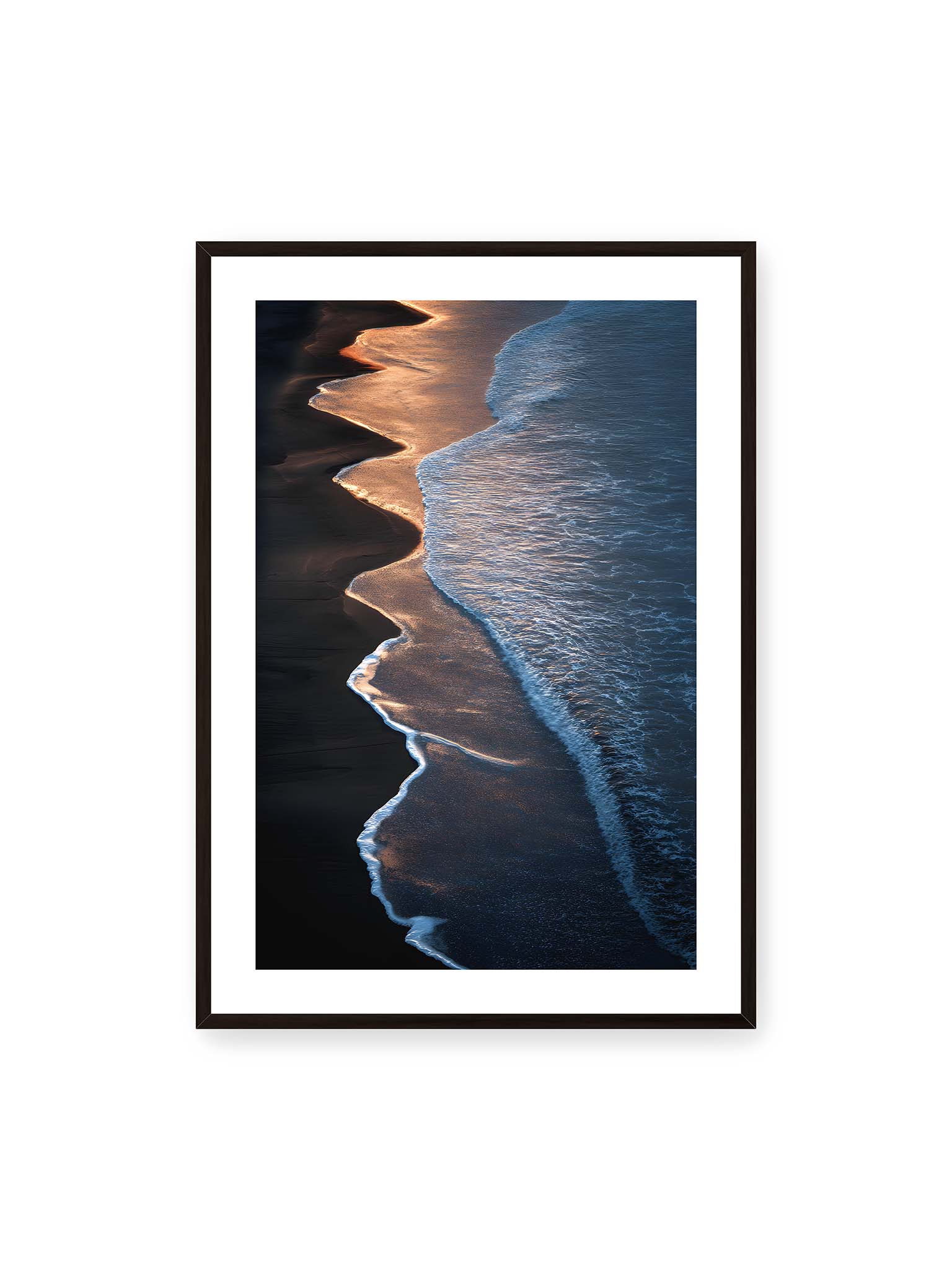 70x100 cm, weißer Galerie-Rand, schwarzer Rahmen – Goldene Wellenlinien treffen auf dunklen Strand mit starkem Kontrast zwischen Licht und Schatten entlang der Küste.