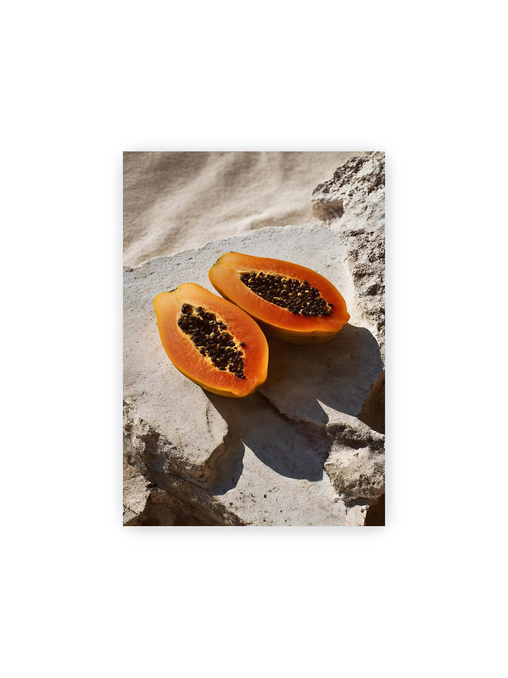 21x30 cm – Zwei halbierte Papayas auf hellem Stein mit dunklen Kernen und leuchtend orangem Fruchtfleisch im direkten Licht.