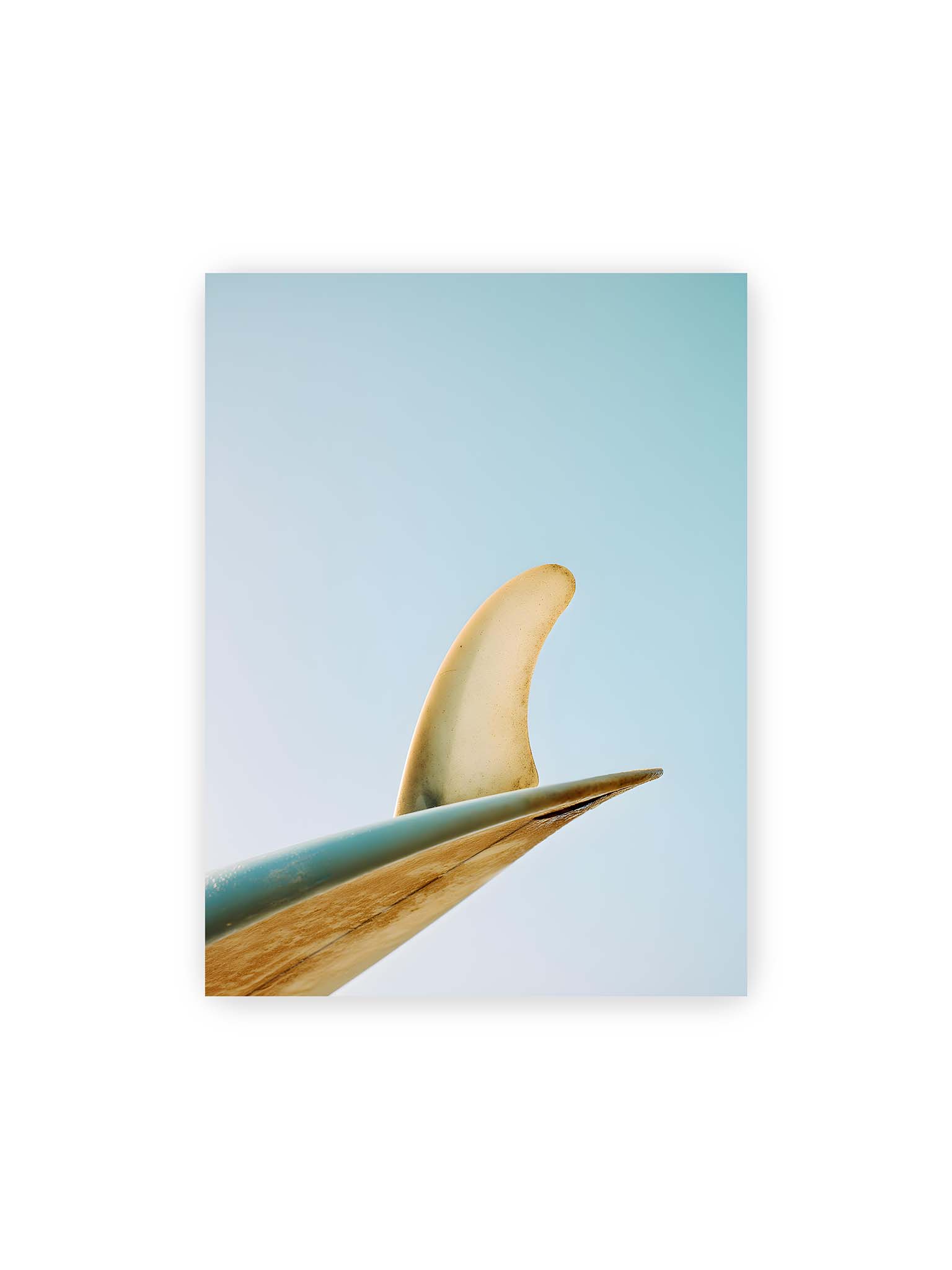 30x40 cm – Surfboard-Finne vor klarem Himmel mit geschwungener Form und minimalistischer Komposition.