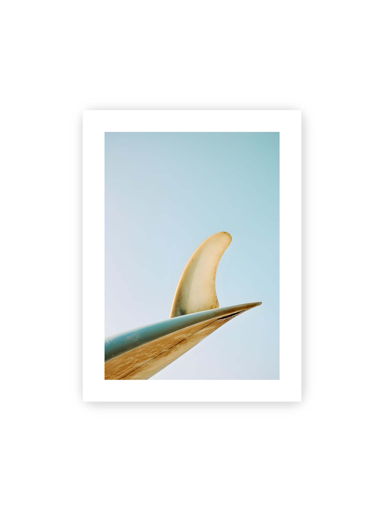 30x40 cm, weißer Galerie-Rand – Surfboard-Finne vor klarem Himmel mit geschwungener Form und minimalistischer Komposition.
