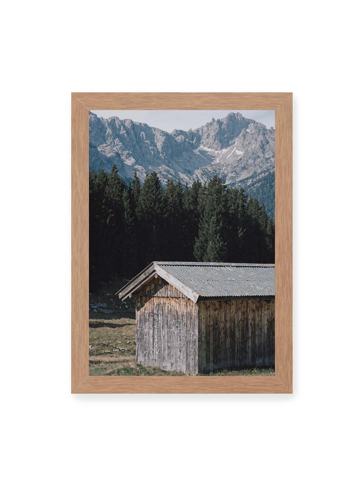 21x30 cm, Eichenrahmen – Verwitterte Holzhütte vor dunklen Nadelbäumen und einer hellen, zerklüfteten Bergkulisse.