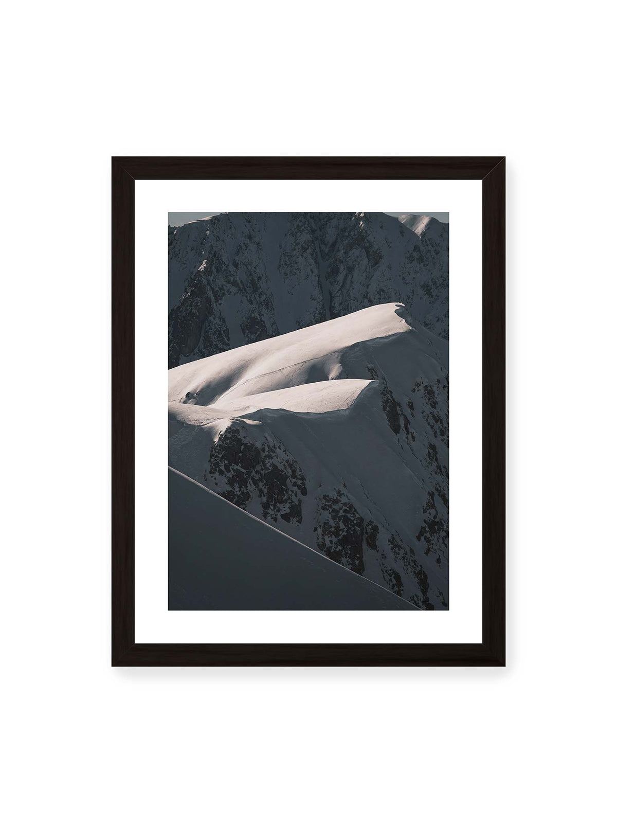 30x40 cm, weißer Galerie-Rand, schwarzer Rahmen – Verschneite Bergrücken mit hellen Graten und tiefen Schatten vor einer dunklen, steilen Felskulisse.