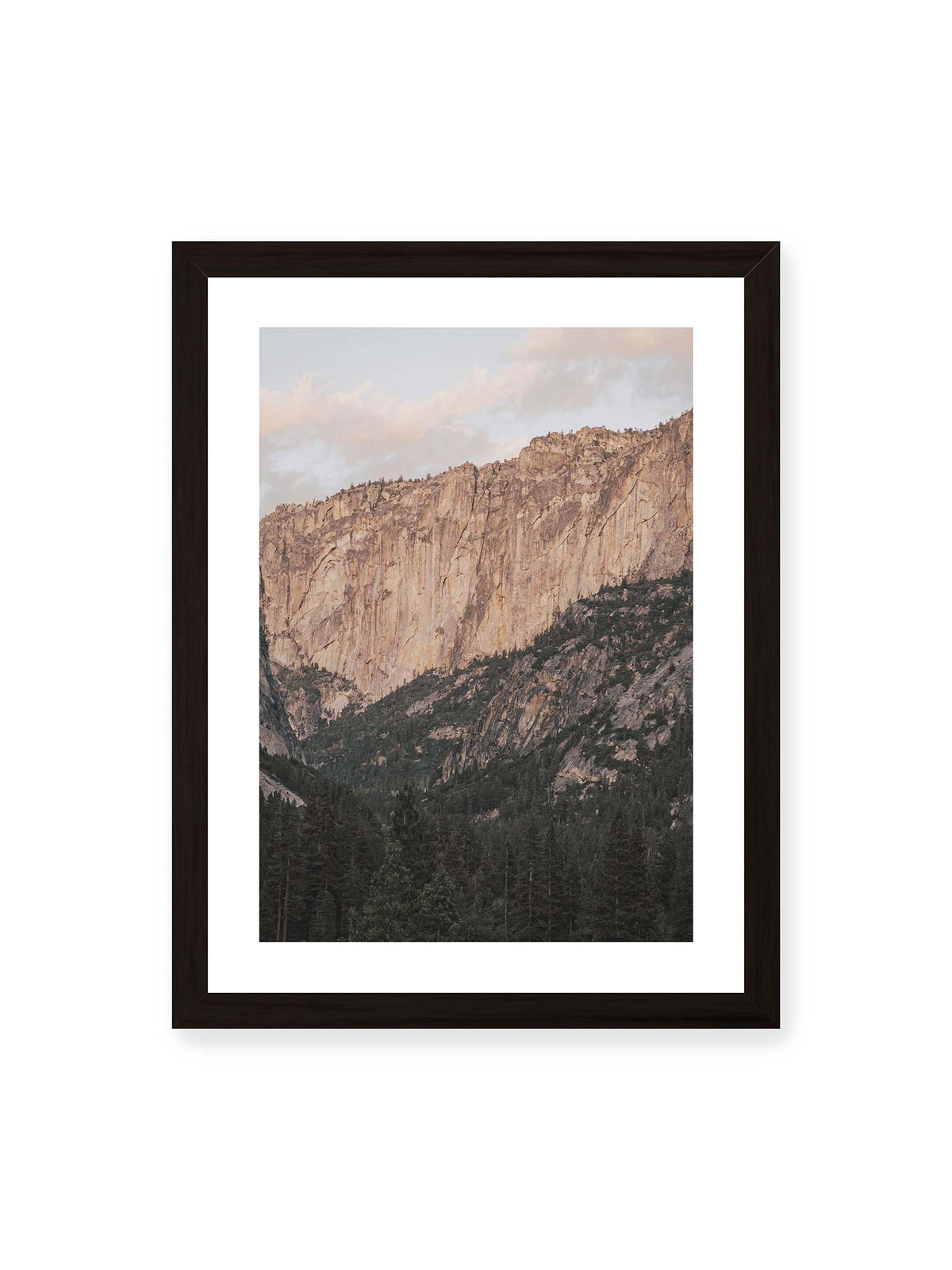 30x40 cm, weißer Galerie-Rand, schwarzer Rahmen – Helle, zerklüftete Felswand über dichtem Nadelwald und dunklen bewaldeten Berghängen.