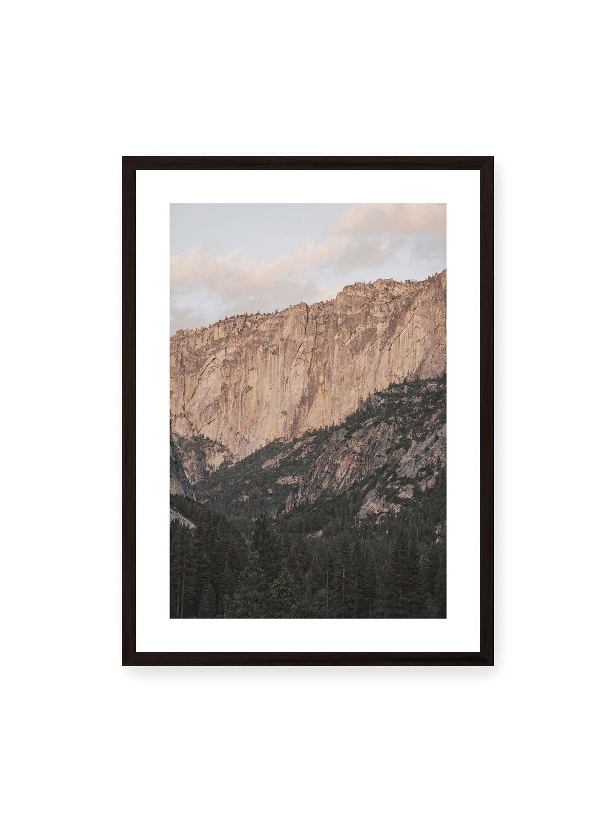 50x70 cm, weißer Galerie-Rand, schwarzer Rahmen – Helle, zerklüftete Felswand über dichtem Nadelwald und dunklen bewaldeten Berghängen.