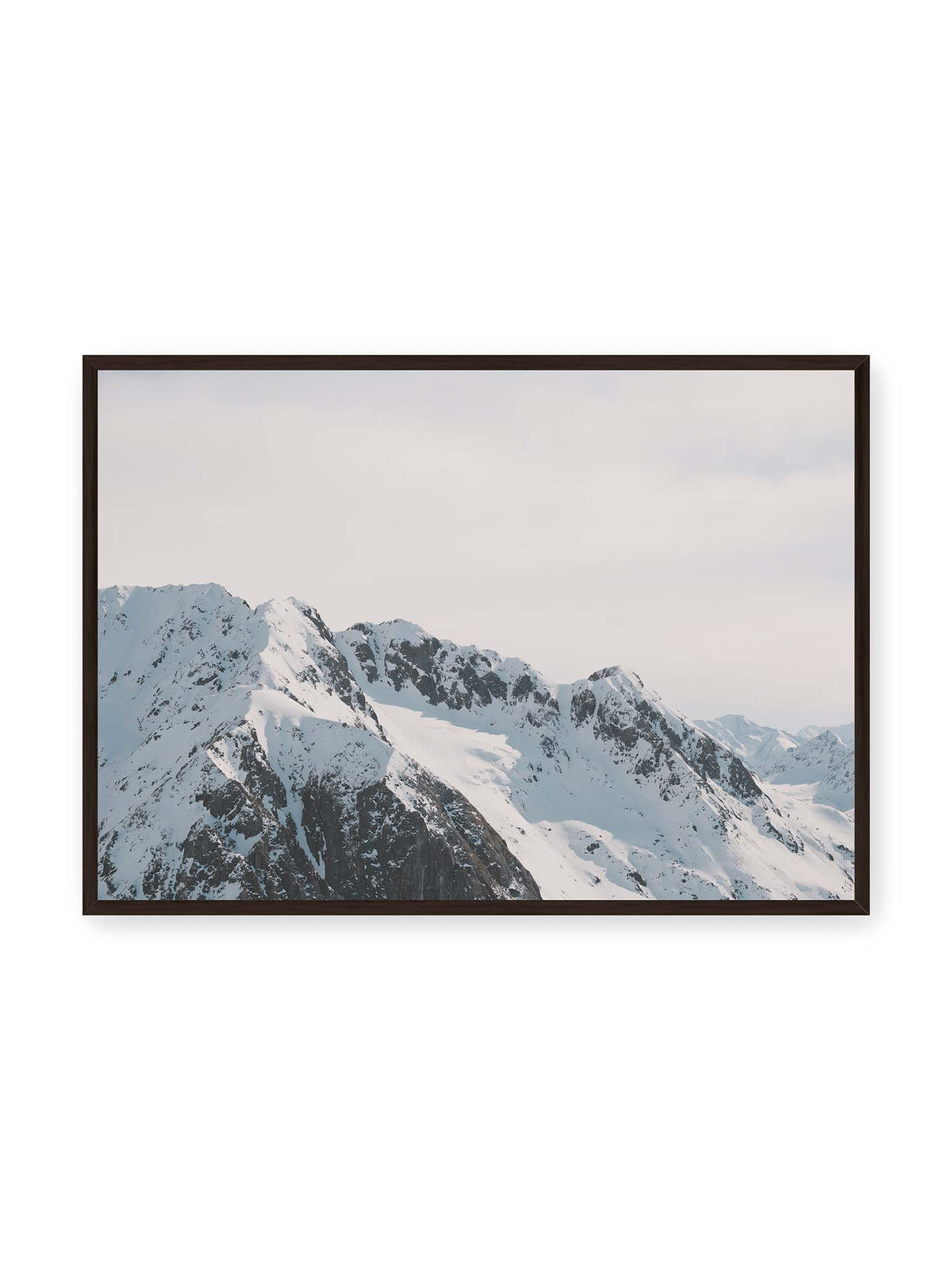100x70 cm, schwarzer Rahmen – Verschneite Bergkette mit schroffen Felswänden und gestaffelten Gipfeln unter einem hellen, weiten Himmel.
