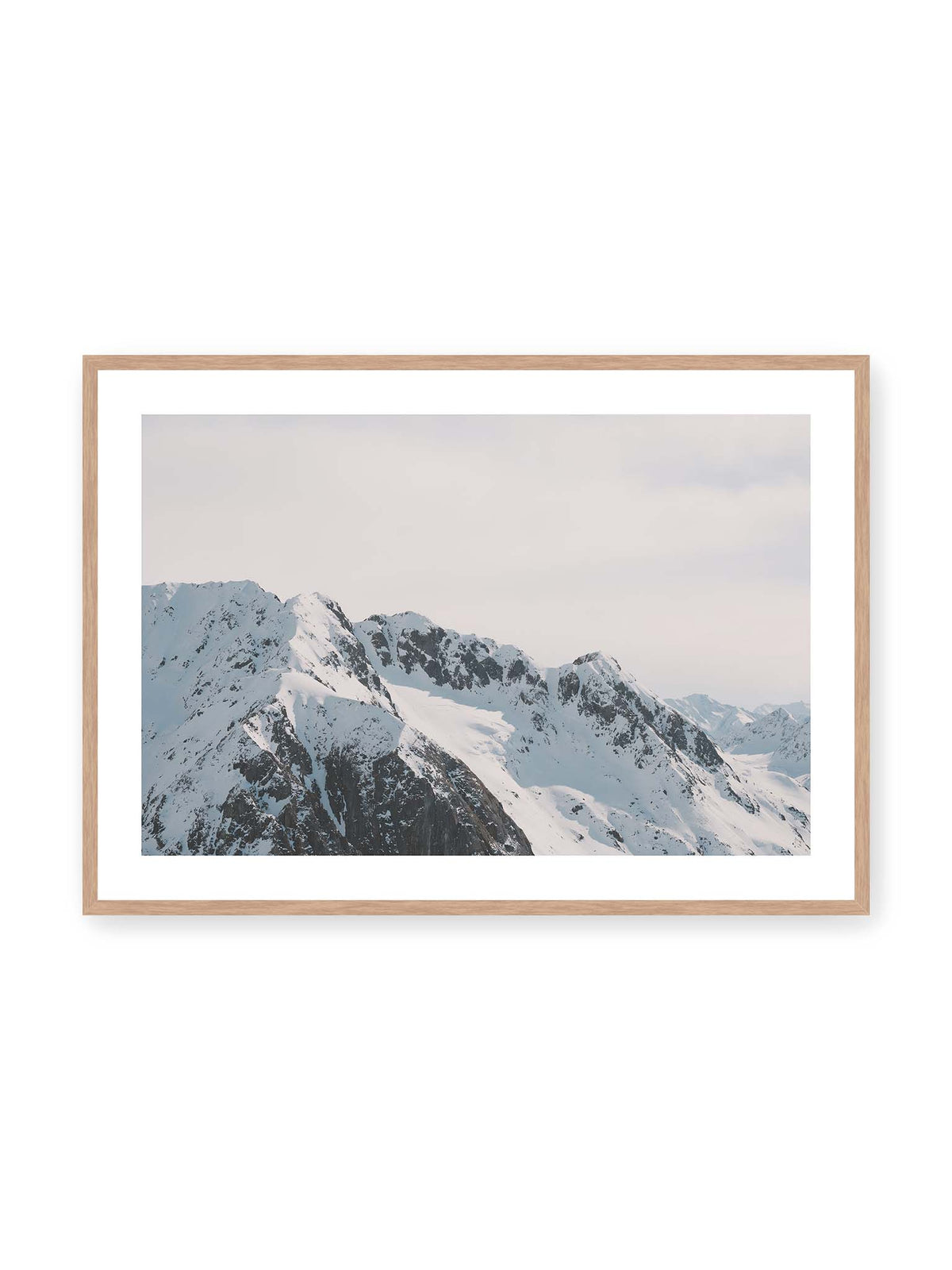 100x70 cm, weißer Galerie-Rand, Eichenrahmen – Verschneite Bergkette mit schroffen Felswänden und gestaffelten Gipfeln unter einem hellen, weiten Himmel.