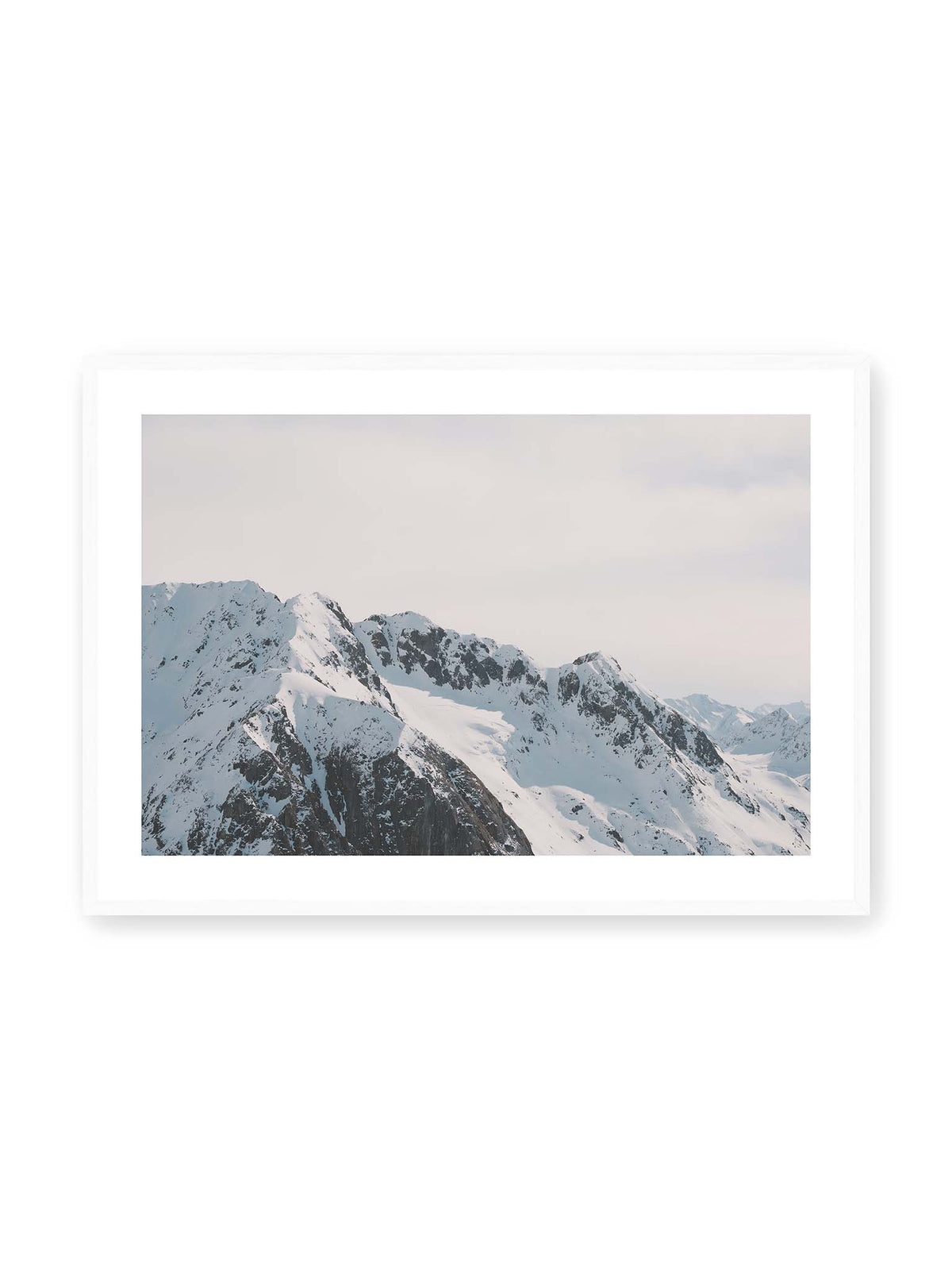100x70 cm, weißer Galerie-Rand, weißer Rahmen – Verschneite Bergkette mit schroffen Felswänden und gestaffelten Gipfeln unter einem hellen, weiten Himmel.
