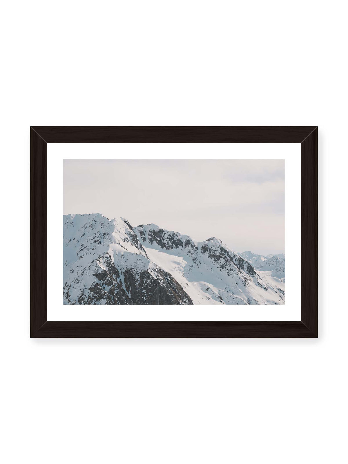 30x21 cm, weißer Galerie-Rand, schwarzer Rahmen – Verschneite Bergkette mit schroffen Felswänden und gestaffelten Gipfeln unter einem hellen, weiten Himmel.