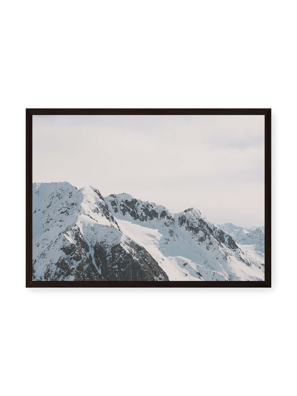 70x50 cm, schwarzer Rahmen – Verschneite Bergkette mit schroffen Felswänden und gestaffelten Gipfeln unter einem hellen, weiten Himmel.
