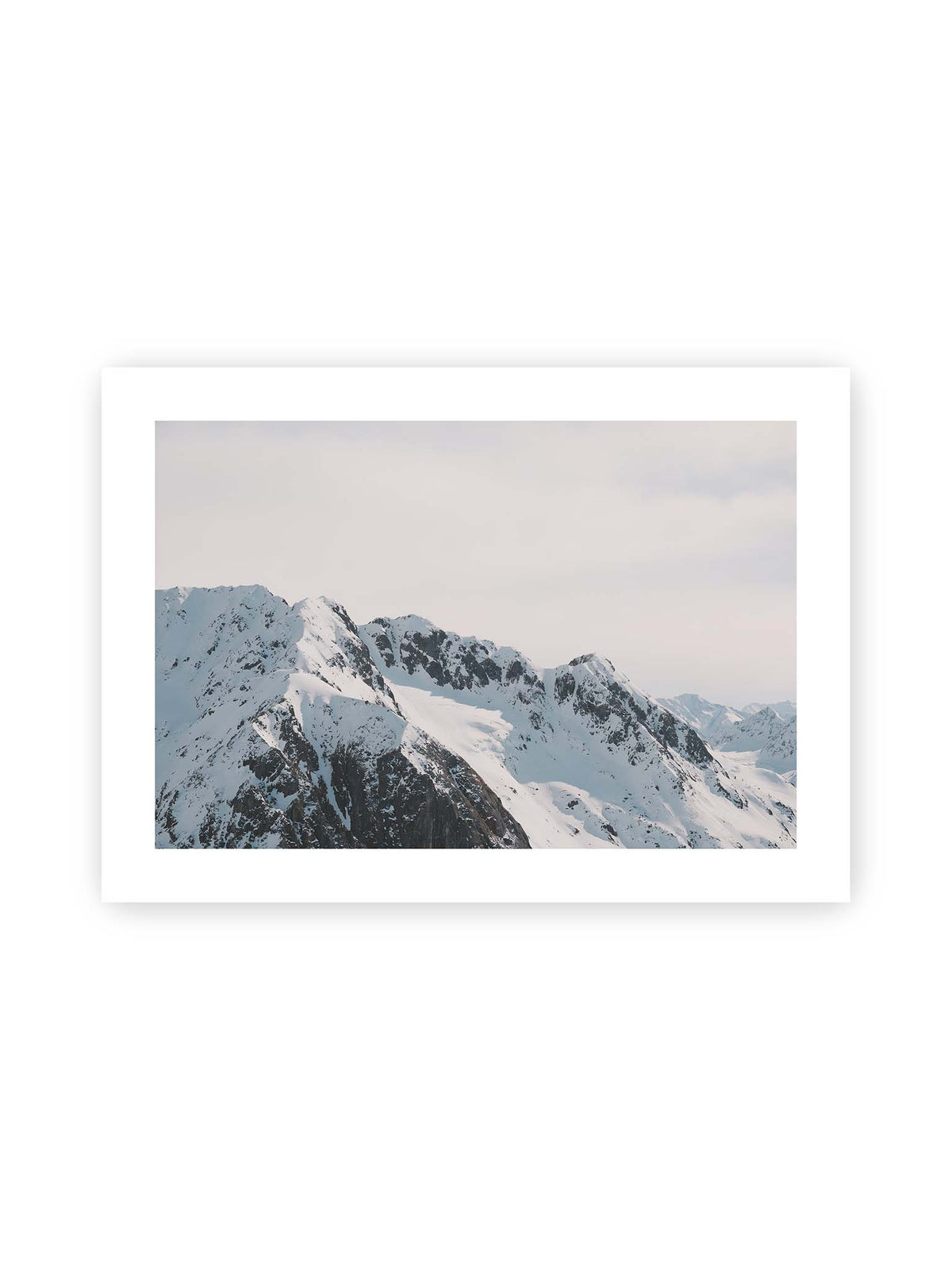 70x50 cm, weißer Galerie-Rand – Verschneite Bergkette mit schroffen Felswänden und gestaffelten Gipfeln unter einem hellen, weiten Himmel.