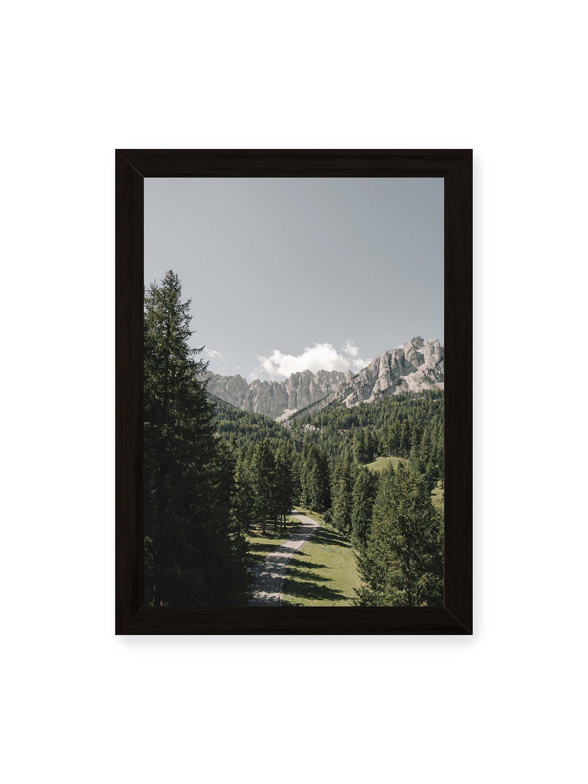 21x30 cm, schwarzer Rahmen – Kurviger Weg durch dichten Nadelwald mit hellen, schroffen Felsformationen im Hintergrund.
