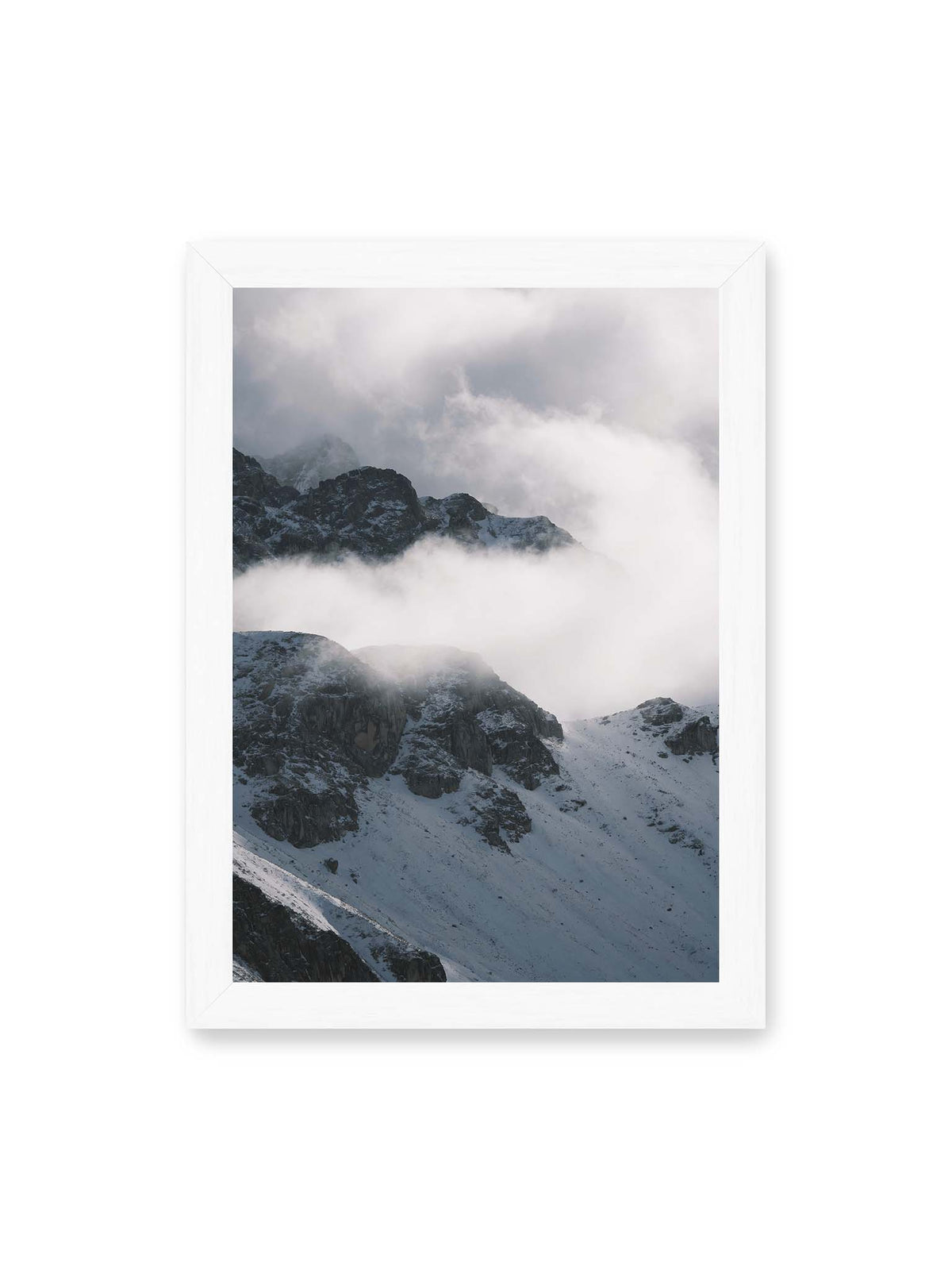 21x30 cm, weißer Rahmen – Verschneite dunkle Felsrücken ragen zwischen dichten, tief ziehenden Wolken hervor.