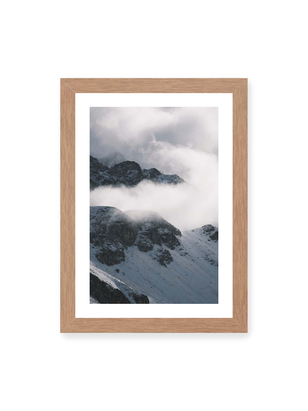 21x30 cm, weißer Galerie-Rand, Eichenrahmen – Verschneite dunkle Felsrücken ragen zwischen dichten, tief ziehenden Wolken hervor.