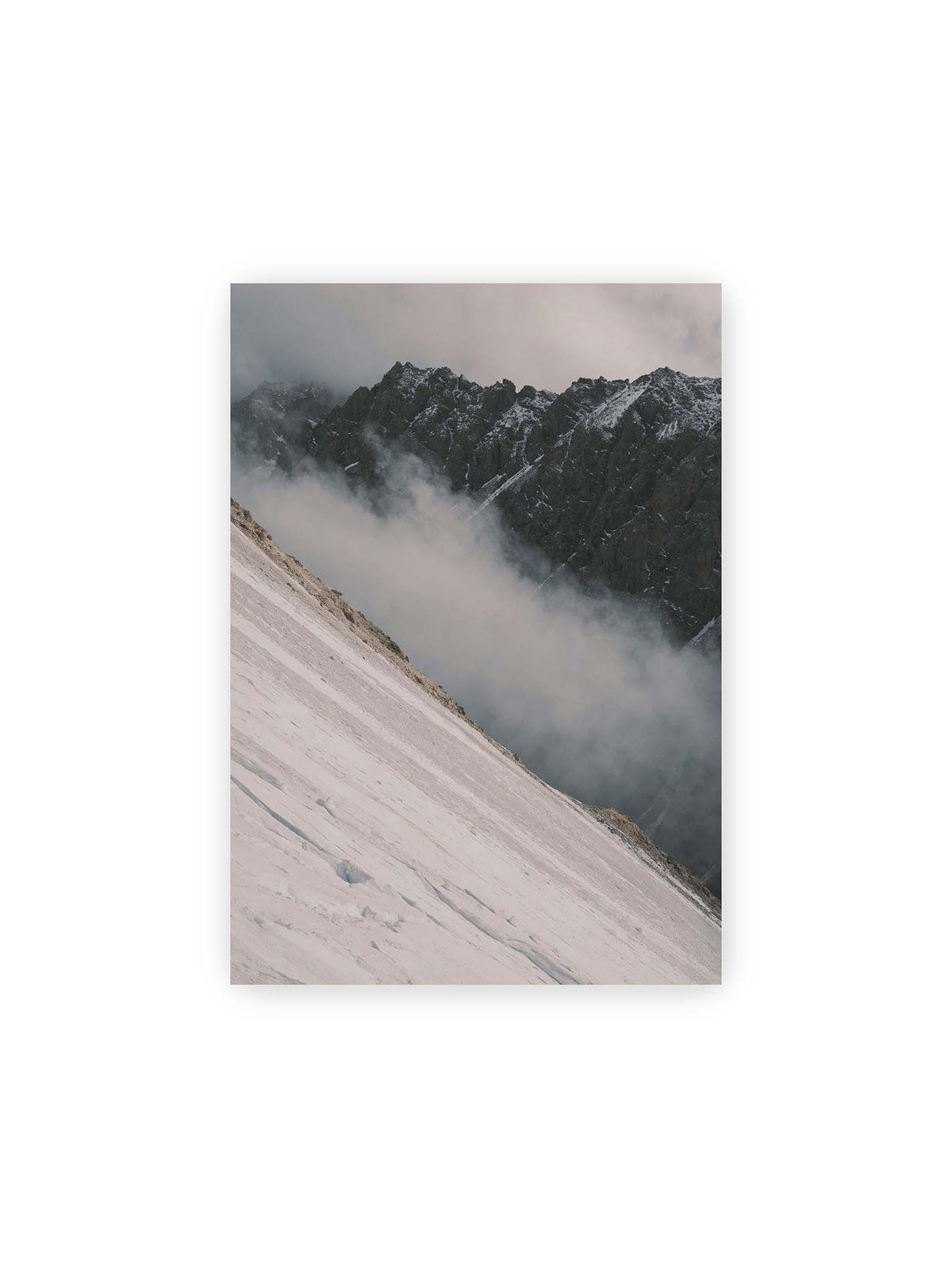 21x30 cm – Diagonale Schneefläche vor dunkler Felswand, durchzogen von tief liegenden Wolken.