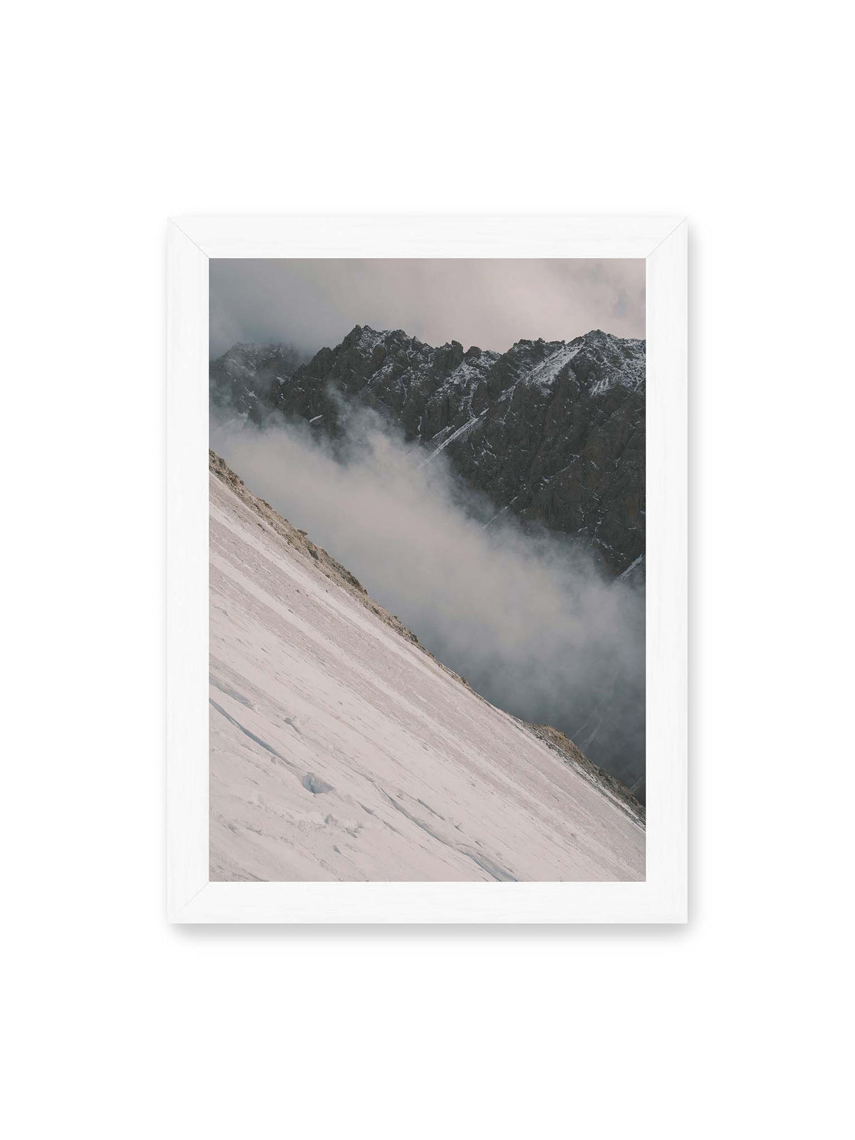 21x30 cm, weißer Rahmen – Diagonale Schneefläche vor dunkler Felswand, durchzogen von tief liegenden Wolken.