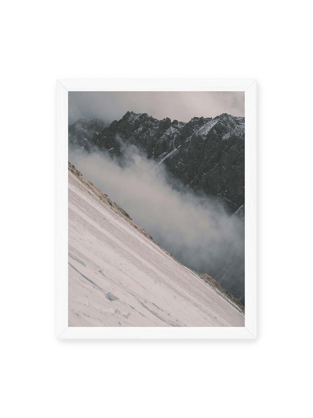 30x40 cm, weißer Rahmen – Diagonale Schneefläche vor dunkler Felswand, durchzogen von tief liegenden Wolken.