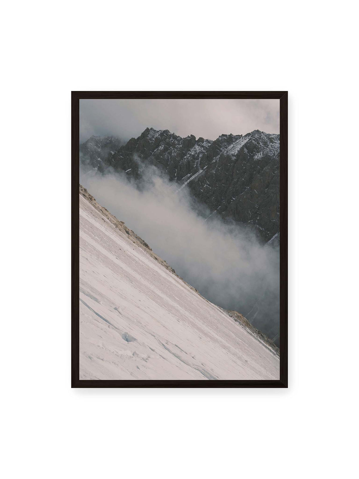 50x70 cm, schwarzer Rahmen – Diagonale Schneefläche vor dunkler Felswand, durchzogen von tief liegenden Wolken.