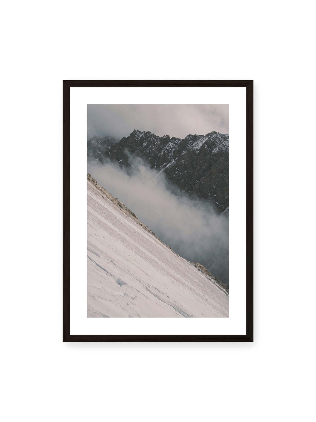 50x70 cm, weißer Galerie-Rand, schwarzer Rahmen – Diagonale Schneefläche vor dunkler Felswand, durchzogen von tief liegenden Wolken.
