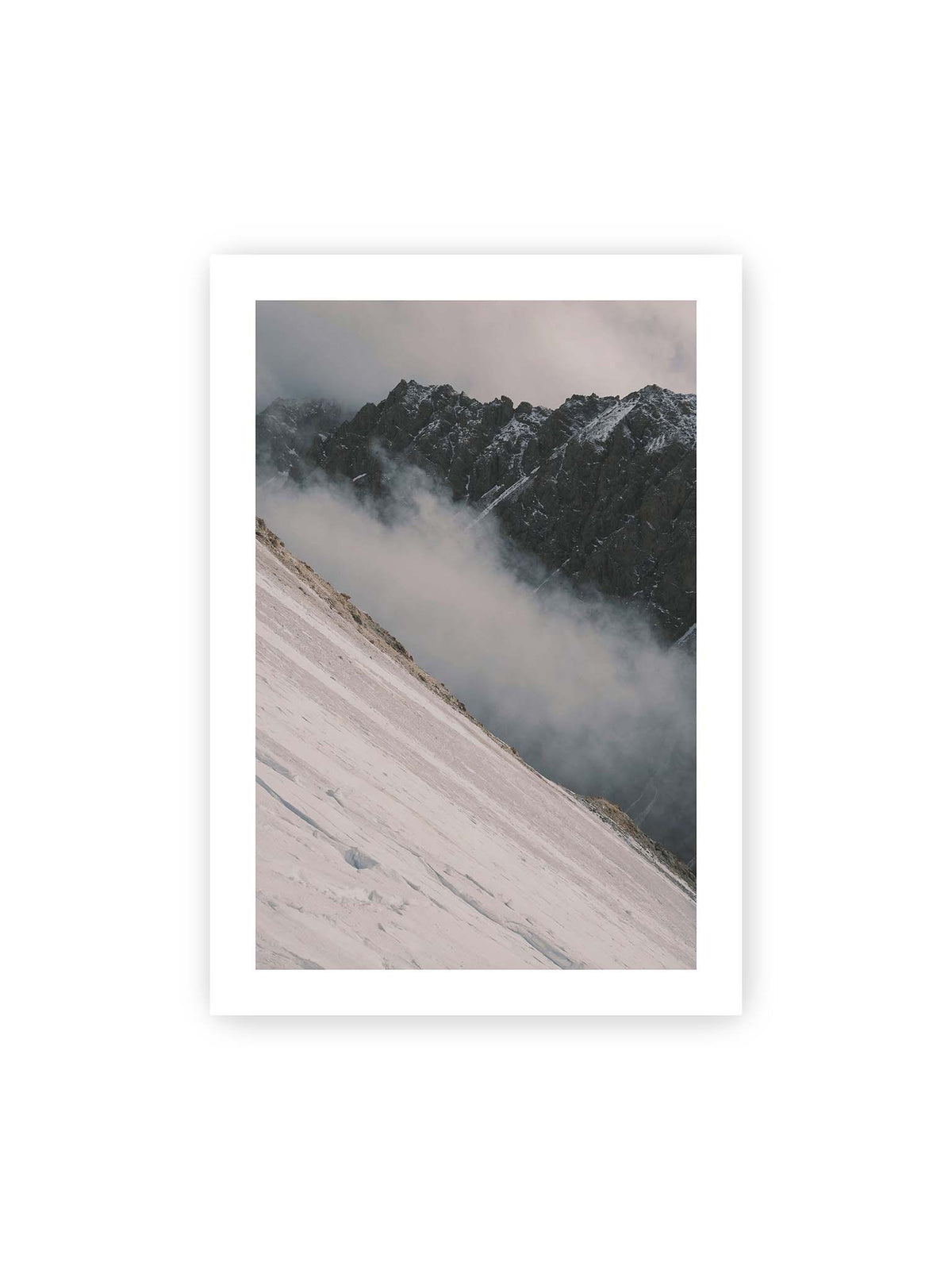 70x100 cm, weißer Galerie-Rand – Diagonale Schneefläche vor dunkler Felswand, durchzogen von tief liegenden Wolken.