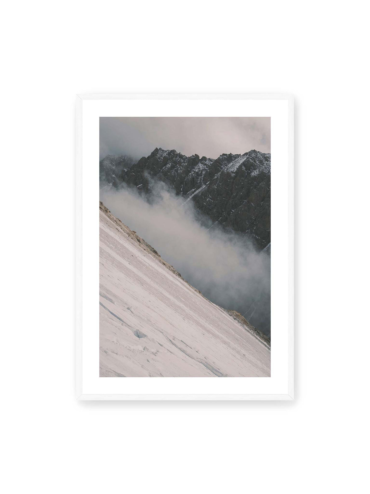 70x100 cm, weißer Galerie-Rand, weißer Rahmen – Diagonale Schneefläche vor dunkler Felswand, durchzogen von tief liegenden Wolken.