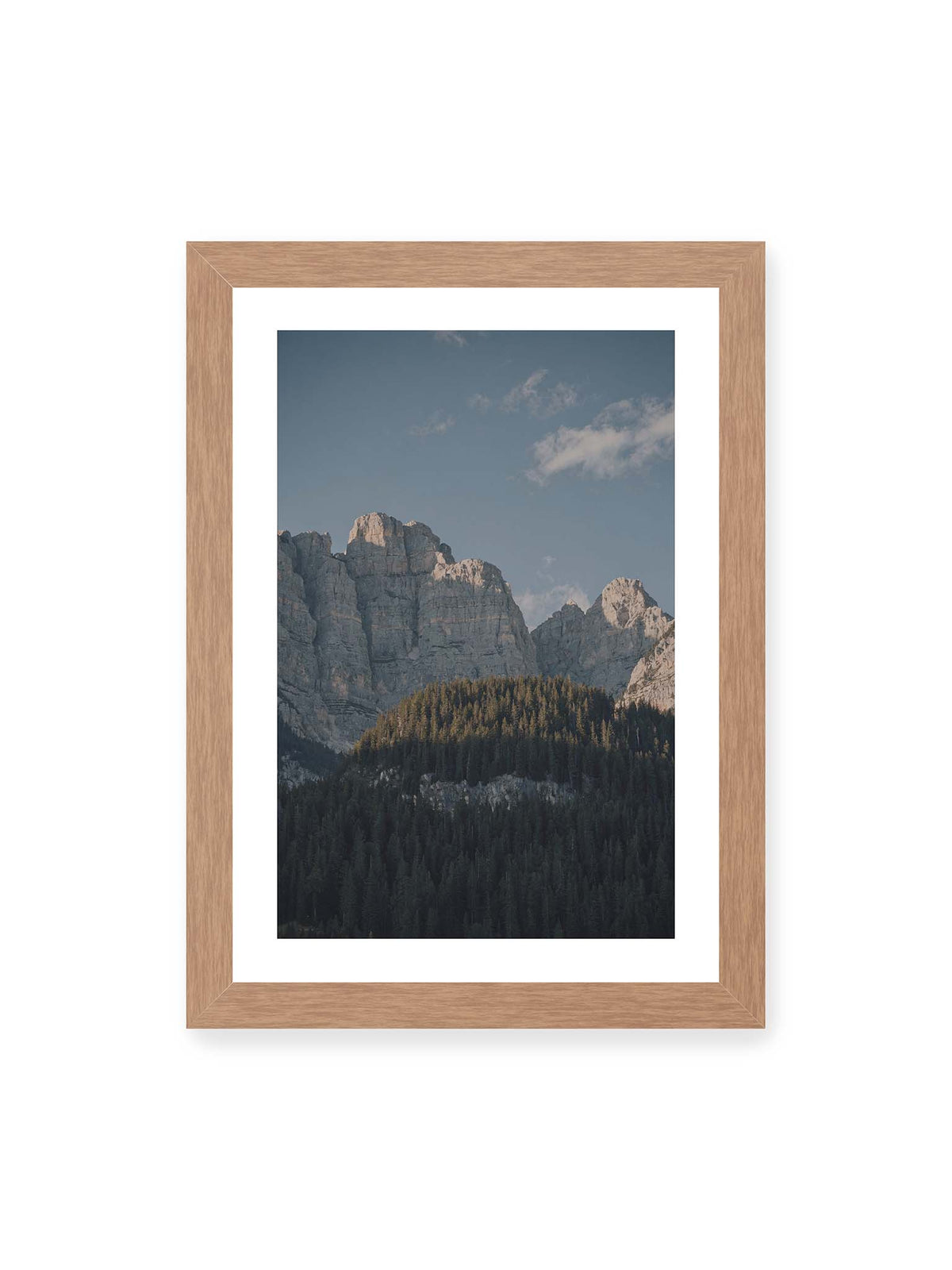 21x30 cm, weißer Galerie-Rand, Eichenrahmen – Helle Felswände erheben sich über einem dunklen Nadelwald vor klarem blauem Himmel.