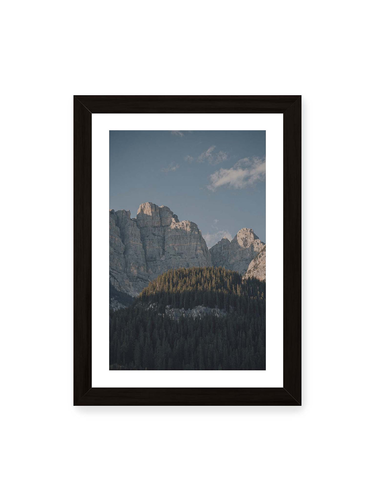 21x30 cm, weißer Galerie-Rand, schwarzer Rahmen – Helle Felswände erheben sich über einem dunklen Nadelwald vor klarem blauem Himmel.