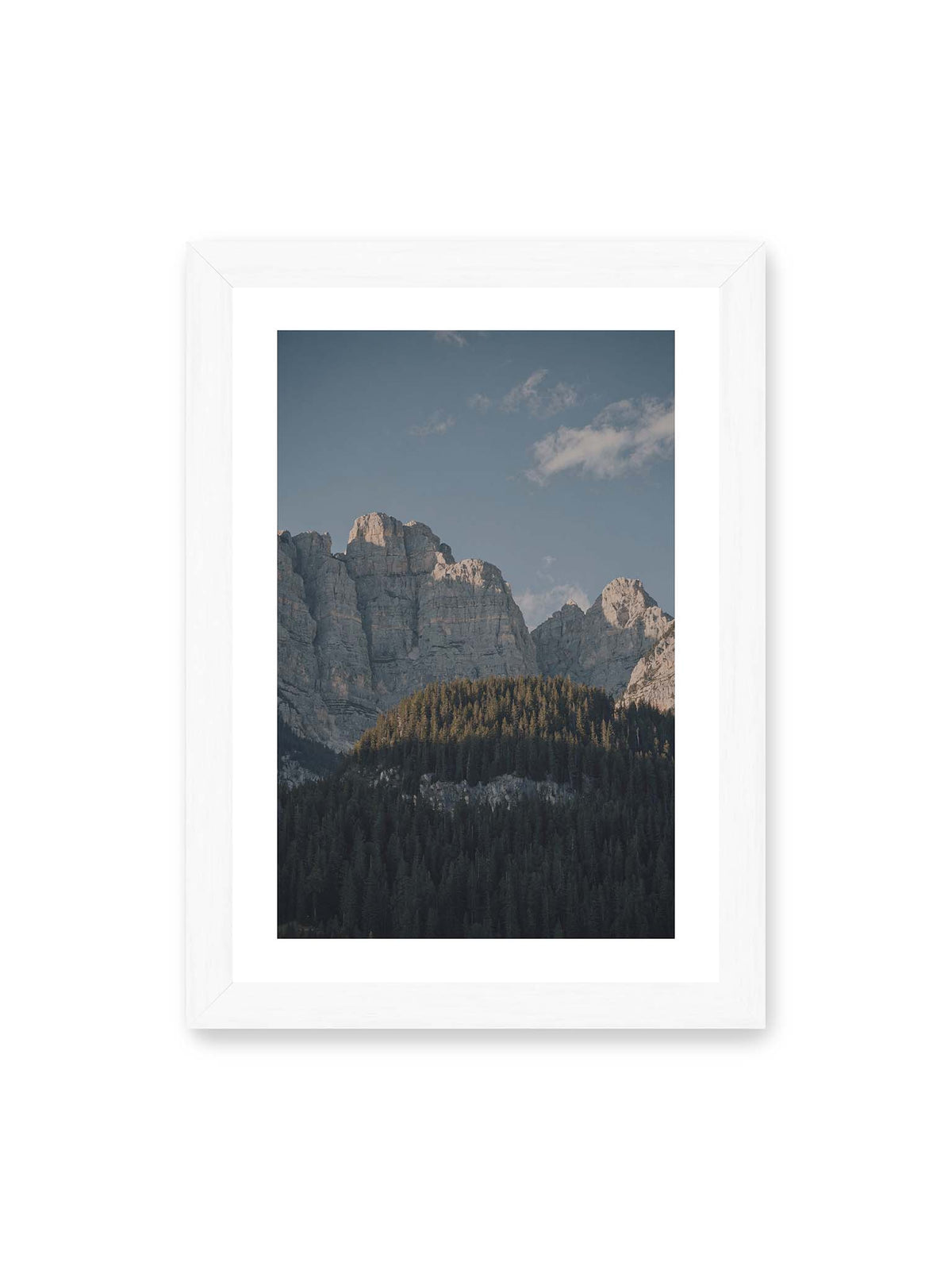 21x30 cm, weißer Galerie-Rand, weißer Rahmen – Helle Felswände erheben sich über einem dunklen Nadelwald vor klarem blauem Himmel.
