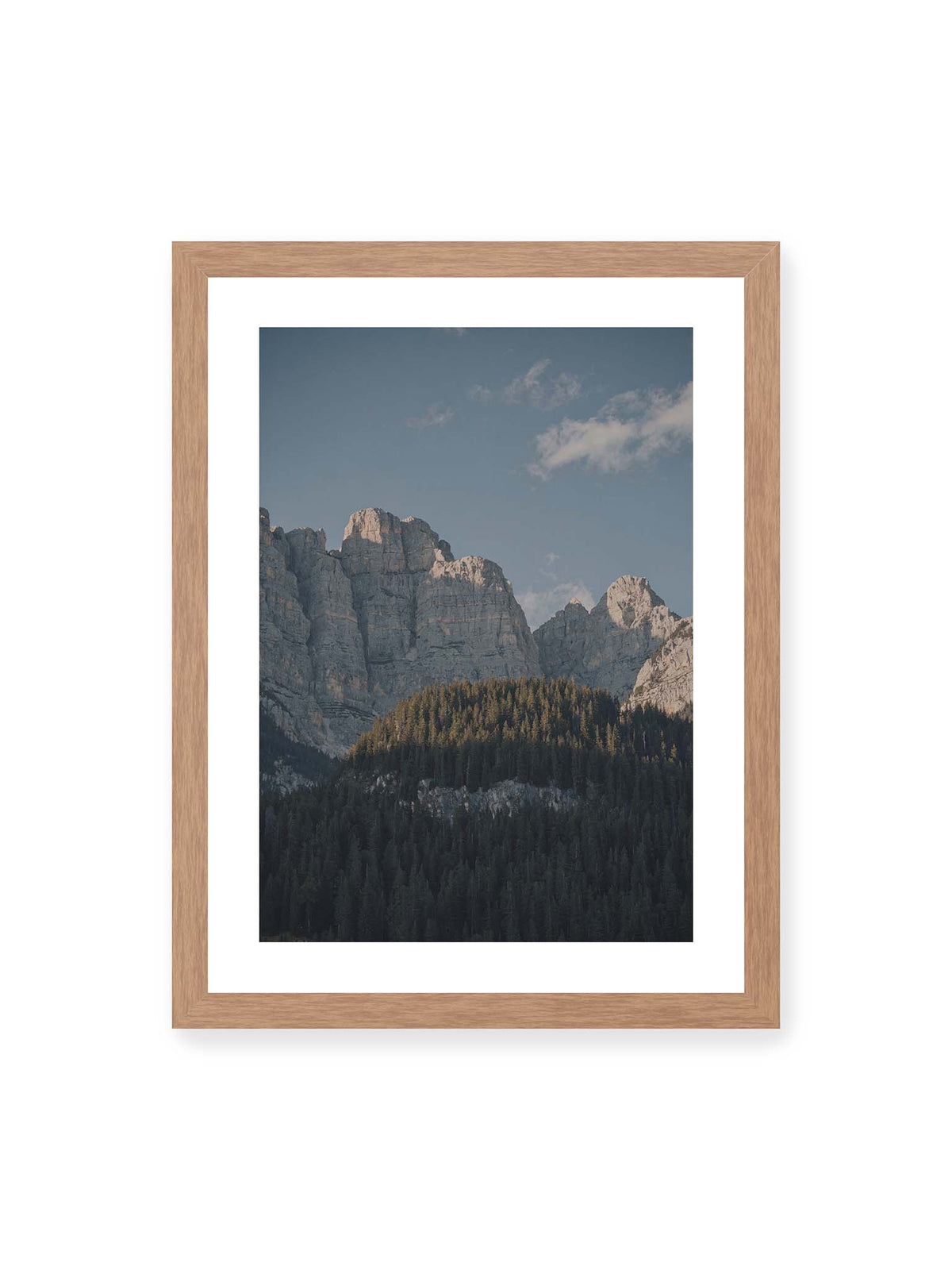 30x40 cm, weißer Galerie-Rand, Eichenrahmen – Helle Felswände erheben sich über einem dunklen Nadelwald vor klarem blauem Himmel.
