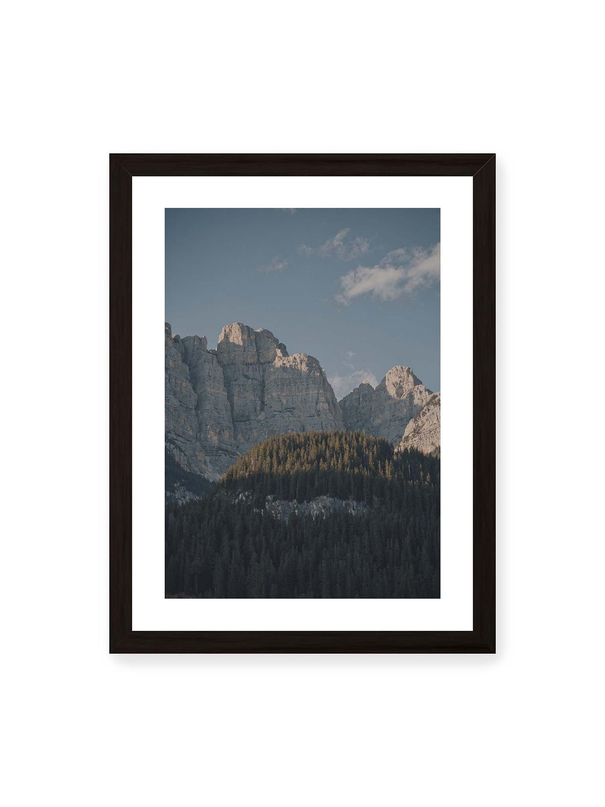 30x40 cm, weißer Galerie-Rand, schwarzer Rahmen – Helle Felswände erheben sich über einem dunklen Nadelwald vor klarem blauem Himmel.