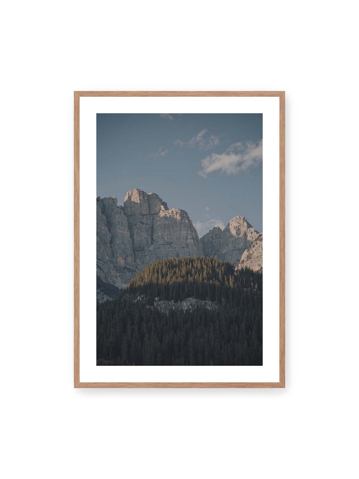 70x100 cm, weißer Galerie-Rand, Eichenrahmen – Helle Felswände erheben sich über einem dunklen Nadelwald vor klarem blauem Himmel.