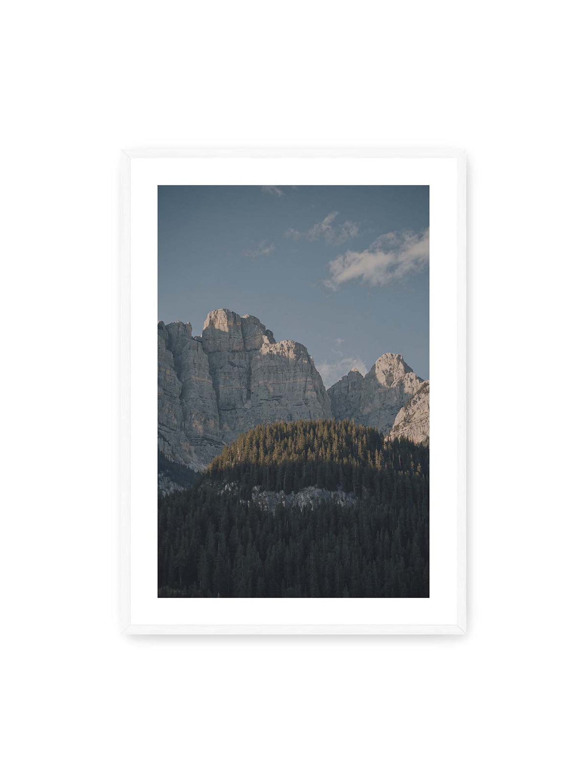 70x100 cm, weißer Galerie-Rand, weißer Rahmen – Helle Felswände erheben sich über einem dunklen Nadelwald vor klarem blauem Himmel.