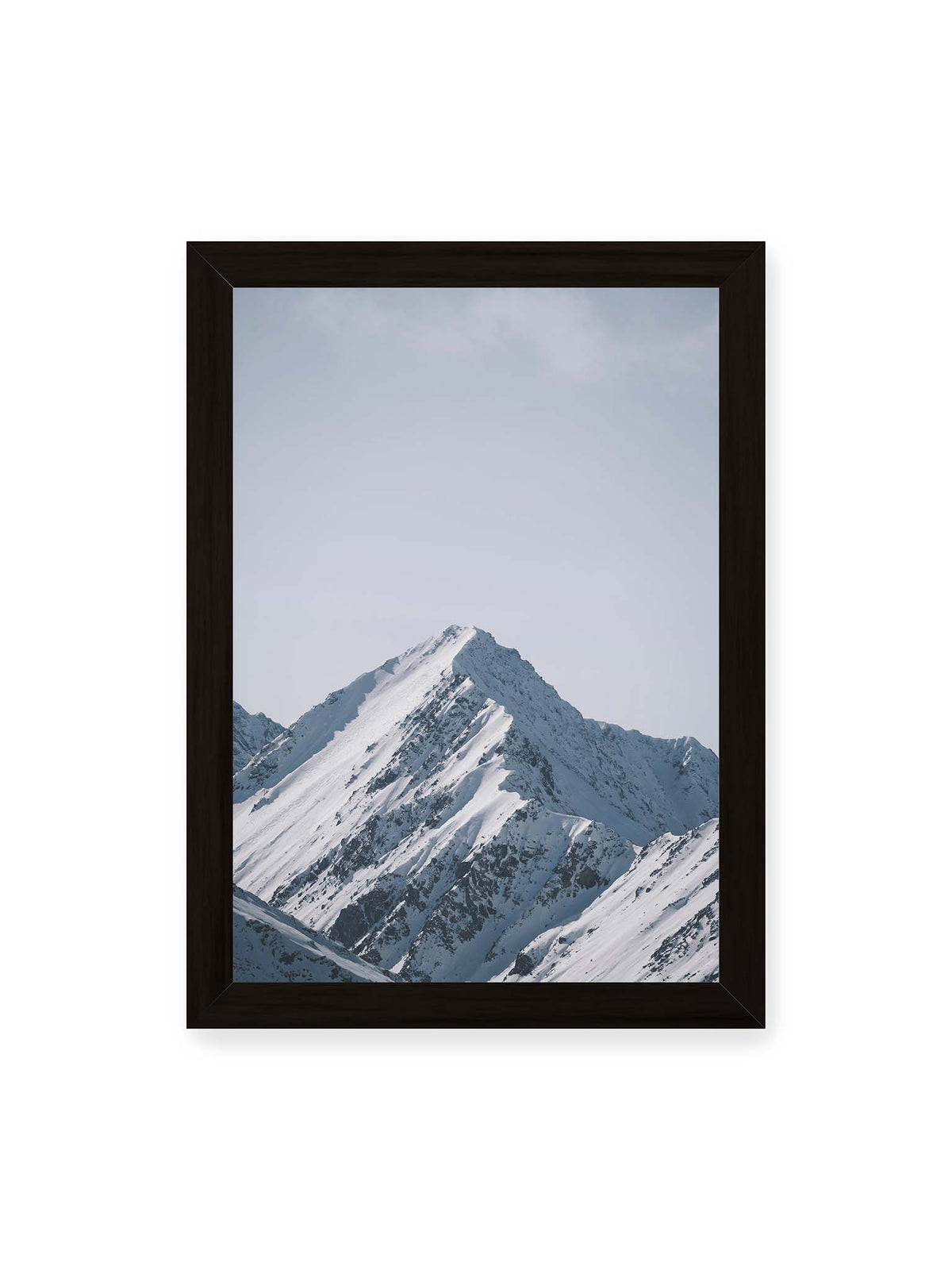 21x30 cm, schwarzer Rahmen – Schneebedeckter Berggipfel mit steilen Graten vor einem weiten blassblauen Himmel.
